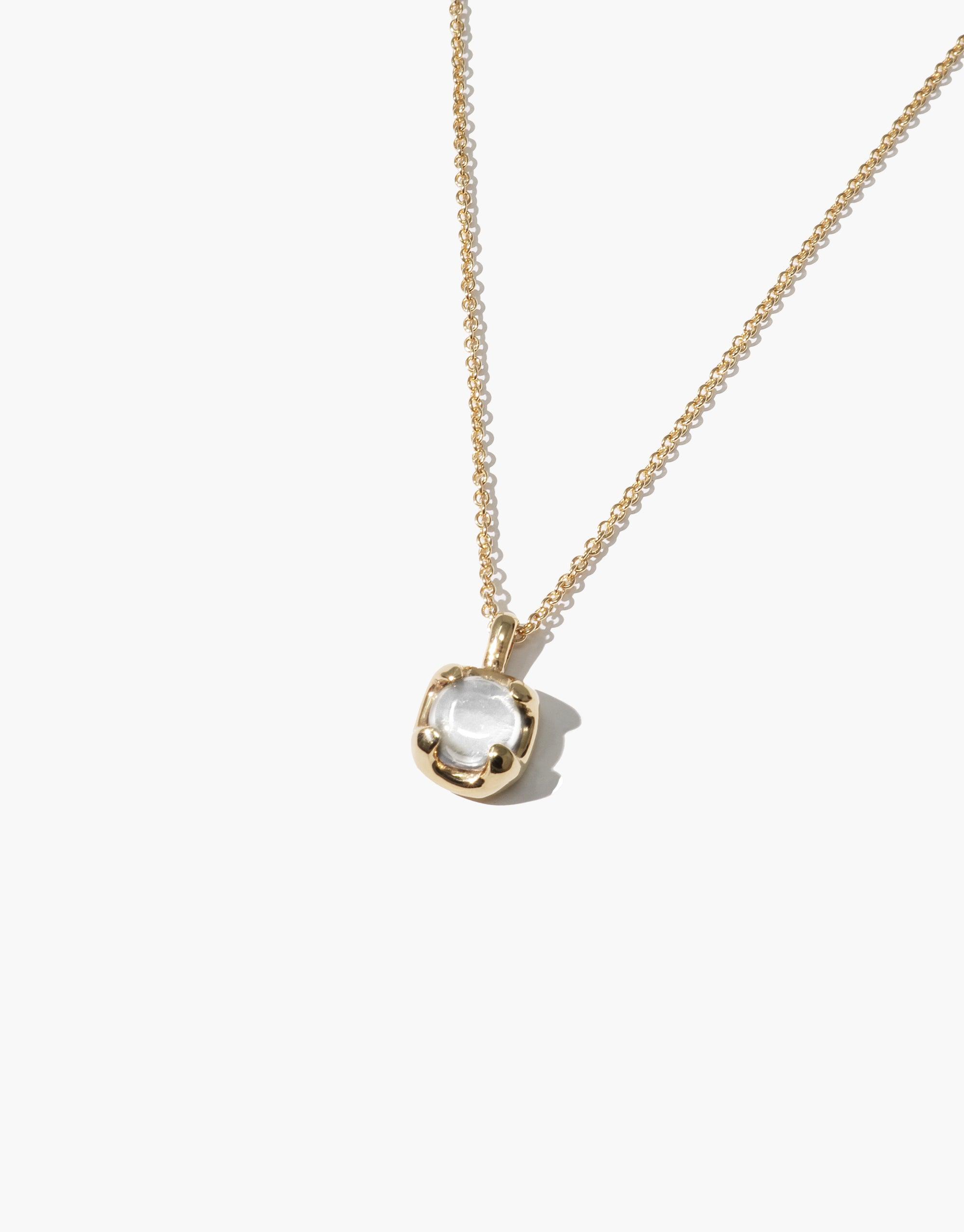 Elegant Beam Necklace featuring a delicate gold chain and a small, round clear gemstone pendant set in a gold-toned bezel. The pendant catches and reflects light, showcasing the eco-friendly design and craftsmanship of CLED's Beam Necklace.