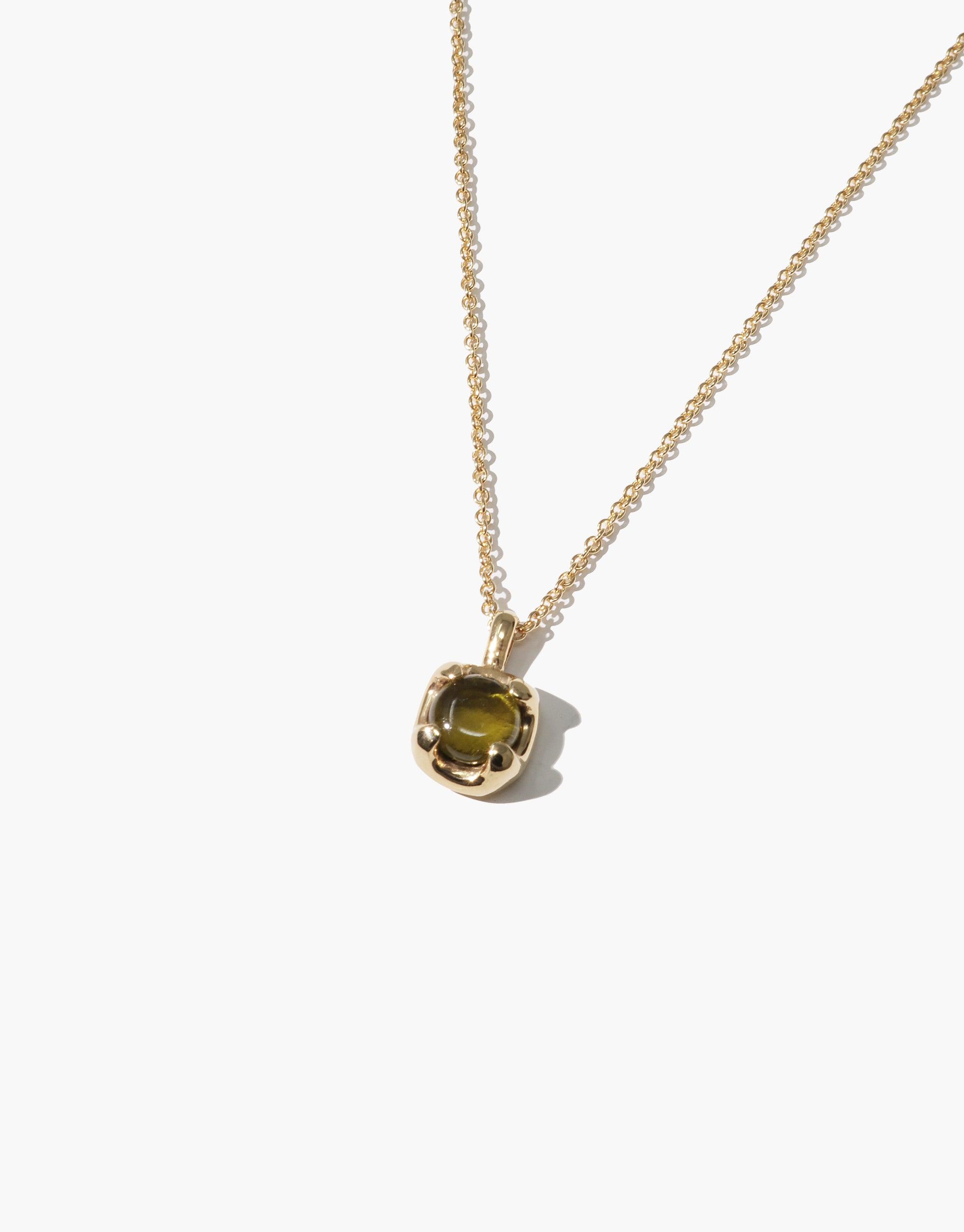 Elegant Beam Necklace featuring a delicate gold chain with a small, round pendant showcasing a vibrant green eco gem. The pendant's setting resembles a sunburst, complementing the gem's radiant appearance. A sustainable and stylish accessory by CLED.