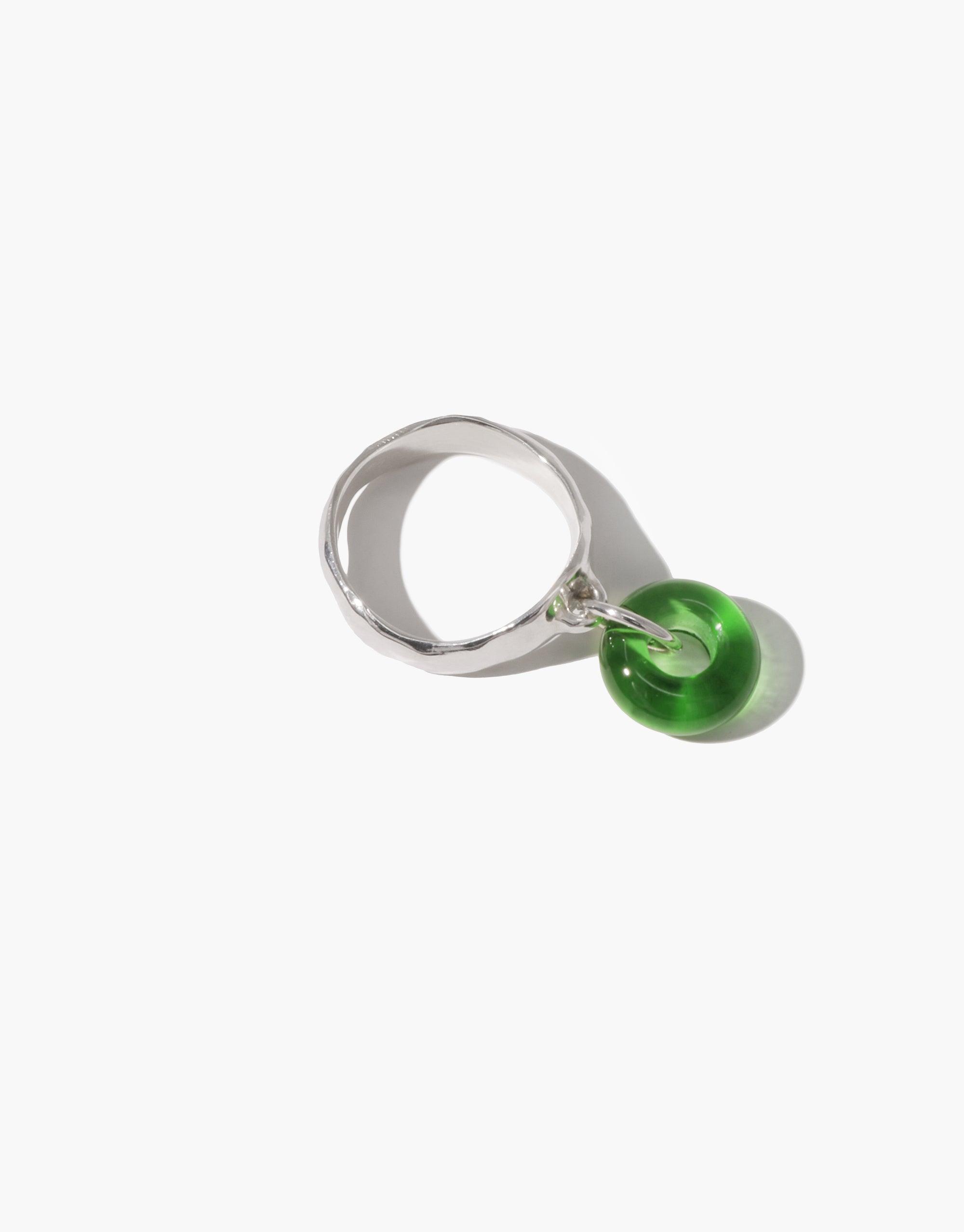 Stylish Donut Dangling Ring featuring a silver-toned band with a vibrant green eco-friendly glass charm. Handcrafted jewelry piece showcasing sustainable design and playful aesthetics. Perfect accessory for environmentally conscious fashion lovers. CLED, Donut Dangling Ring.