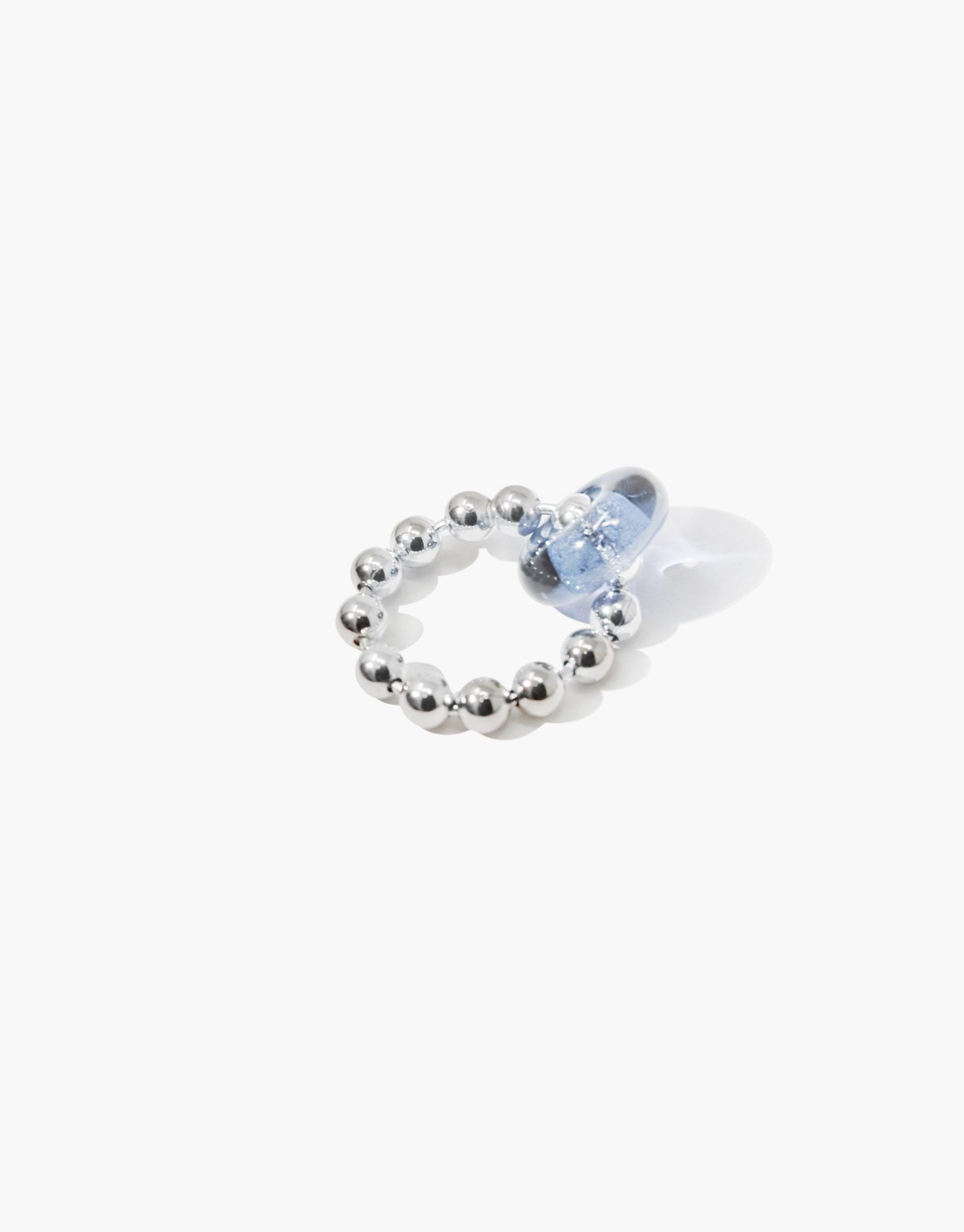 Donut Ball Ring featuring a circular silver beaded band with a light blue glass eco gem, showcasing sustainable jewelry design. Handcrafted ring inspired by prismatic light reflections, perfect for eco-conscious fashion. CLED Donut Ball Ring.
