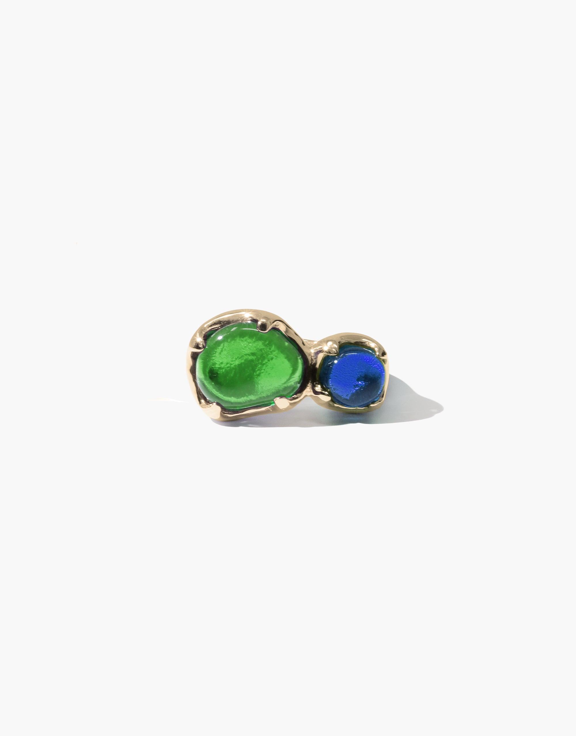 Duo Beam Ring featuring two eco gems, one large green and one small blue, set in a gold-toned metal band. Handcrafted sustainable jewelry showcasing upcycled glass in vibrant colors inspired by prism light refraction. Unique eco-friendly design by CLED.