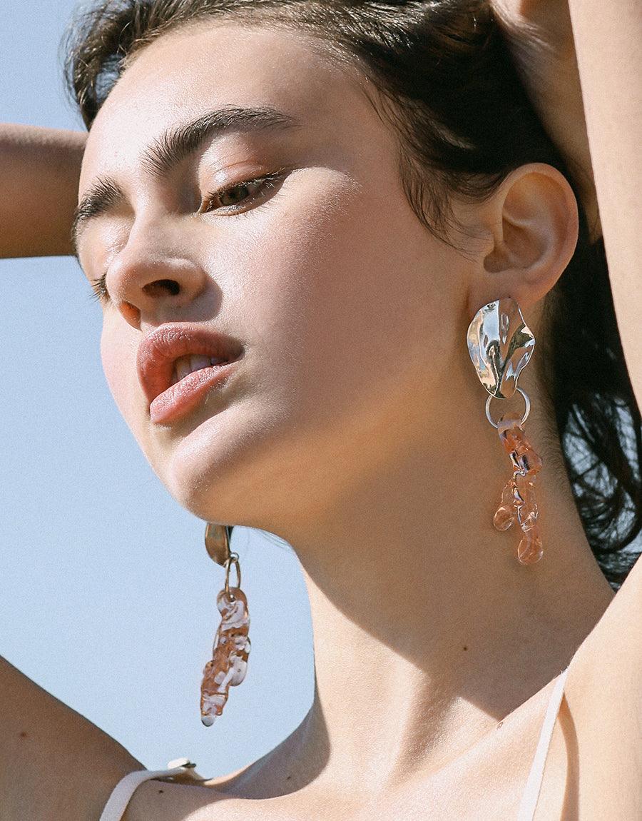Elegant model wearing Coral Reef Earrings, showcasing long dangling design with coral-inspired shapes. Handcrafted from eco-friendly repurposed glass, these statement earrings reflect sustainable luxury and marine beauty. Coral Reef Earrings by CLED.