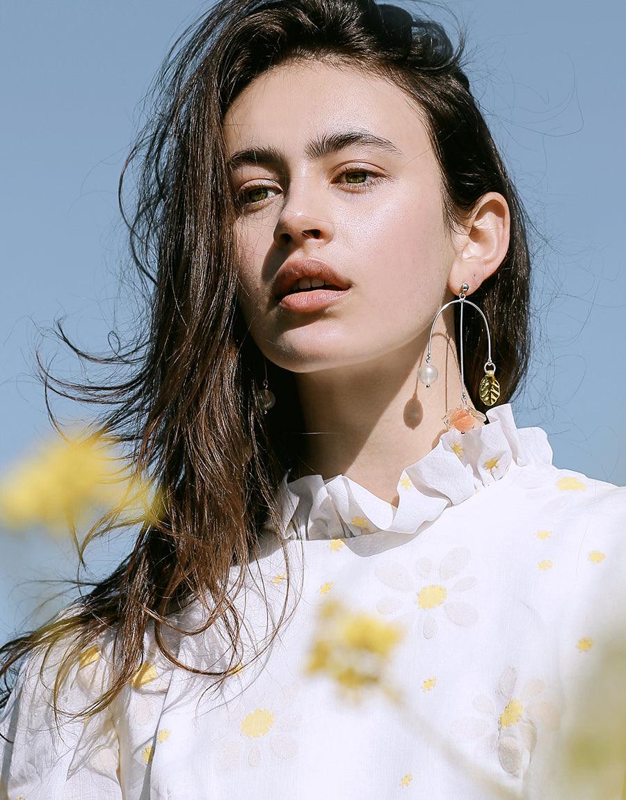 Elegant model wearing Floral Cluster Earrings, long dangling silver earrings with delicate floral accents and eco-friendly glass elements. Styled with white ruffled blouse against blue sky background. Handcrafted sustainable jewelry by CLED.