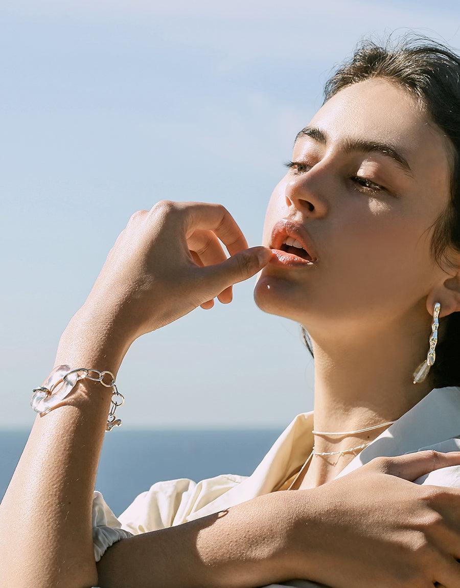 Water Earrings showcased on a woman's ear, featuring artistic asymmetric shapes crafted from repurposed glass. The design embodies eco-conscious elegance, emphasizing water conservation.