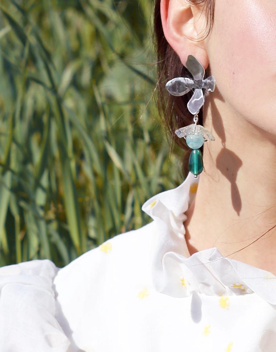 Wildflower Earrings, worn by a woman, showcase sterling silver with detachable Eco Gem charms repurposed from glass bottles, highlighting CLED's eco-conscious craftsmanship.