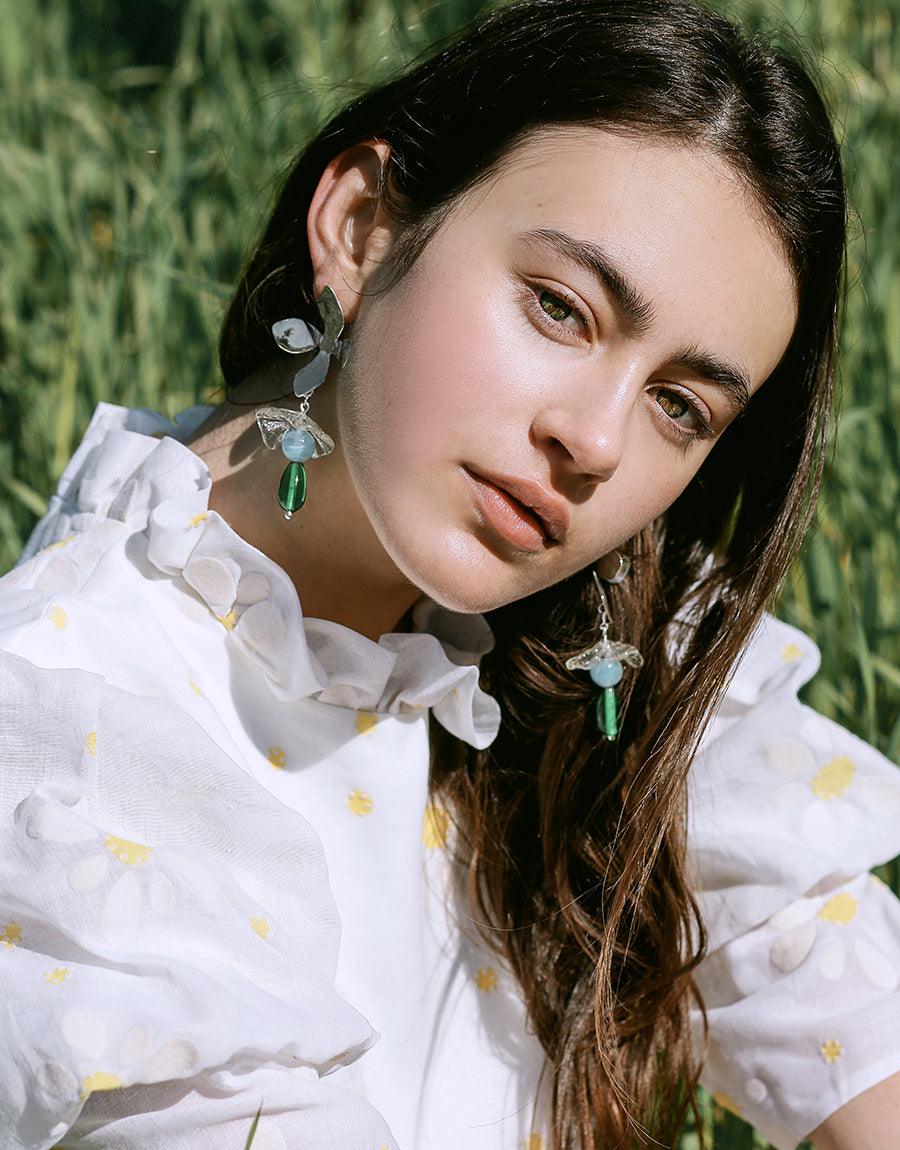 Wildflower Earrings, worn by a woman, showcase sterling silver with detachable Eco Gem charms repurposed from glass bottles, highlighting CLED's eco-conscious craftsmanship.