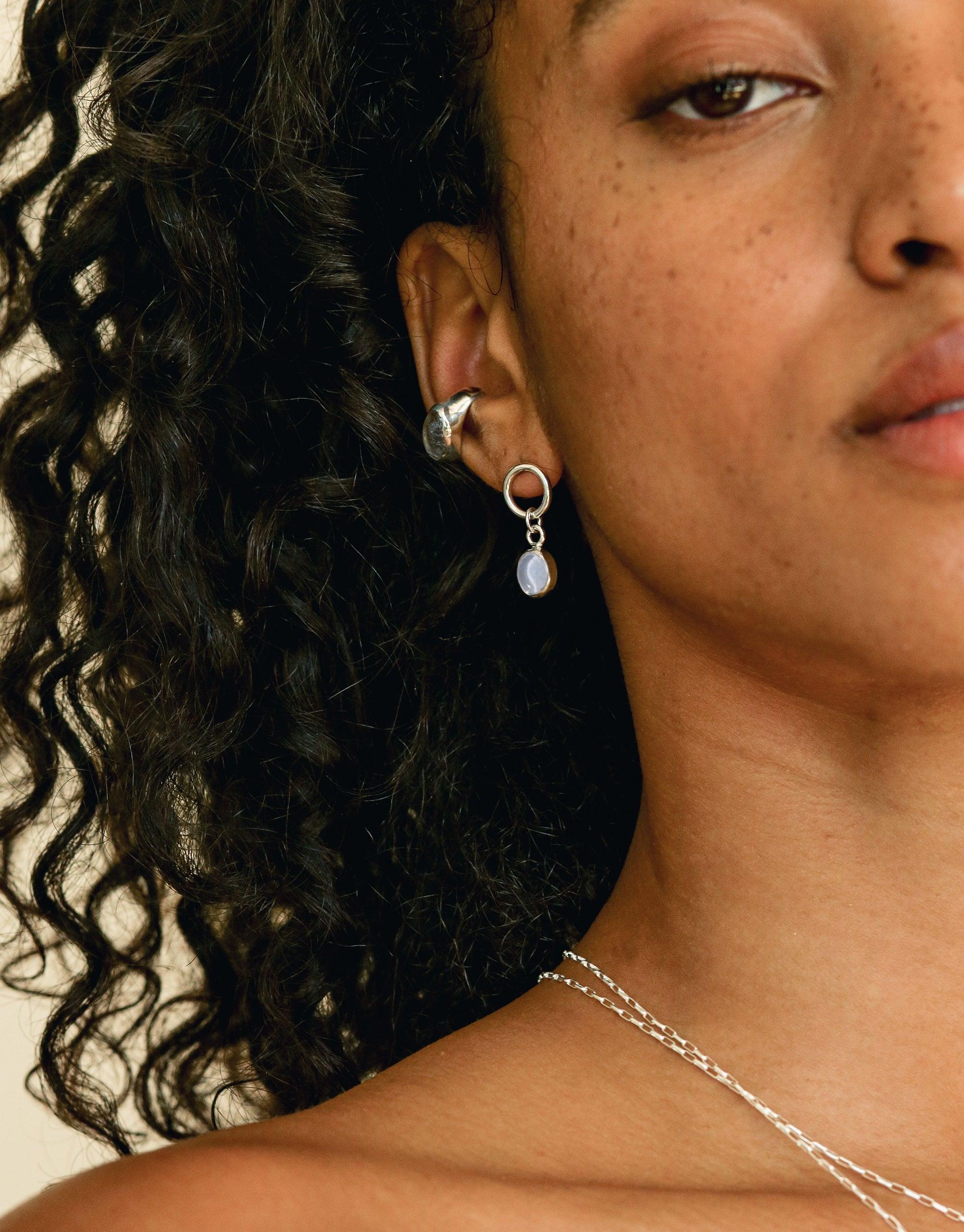 Elegant Oval Dangling Earrings with upcycled eco gems, showcasing delicate silver hoops and teardrop-shaped charms. Handcrafted jewelry inspired by nature, perfect for sustainable fashion enthusiasts. Oval Dangling Earrings by CLED.