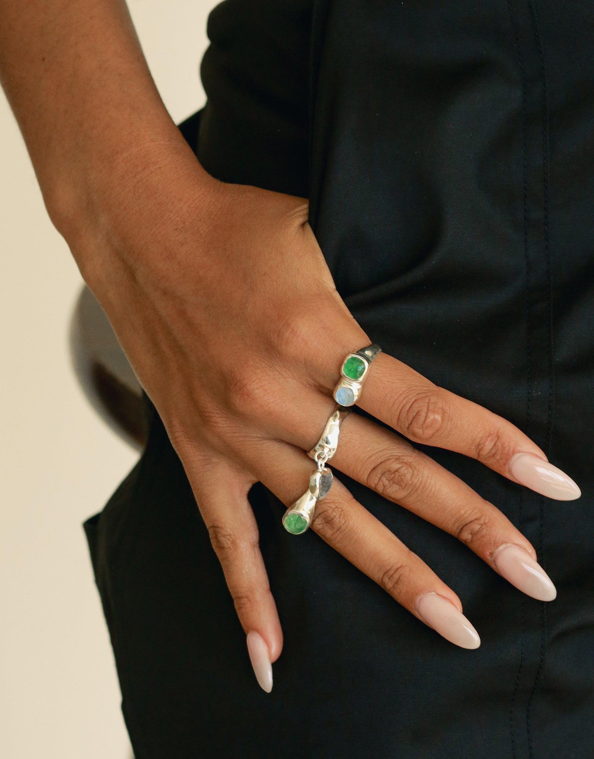 Close-up of a hand wearing the Duo Sculpture Ring, featuring a unique design with green and white eco gems set in a silver band. Elegant and sustainable jewelry piece showcasing upcycled glass charms. Handcrafted by CLED.