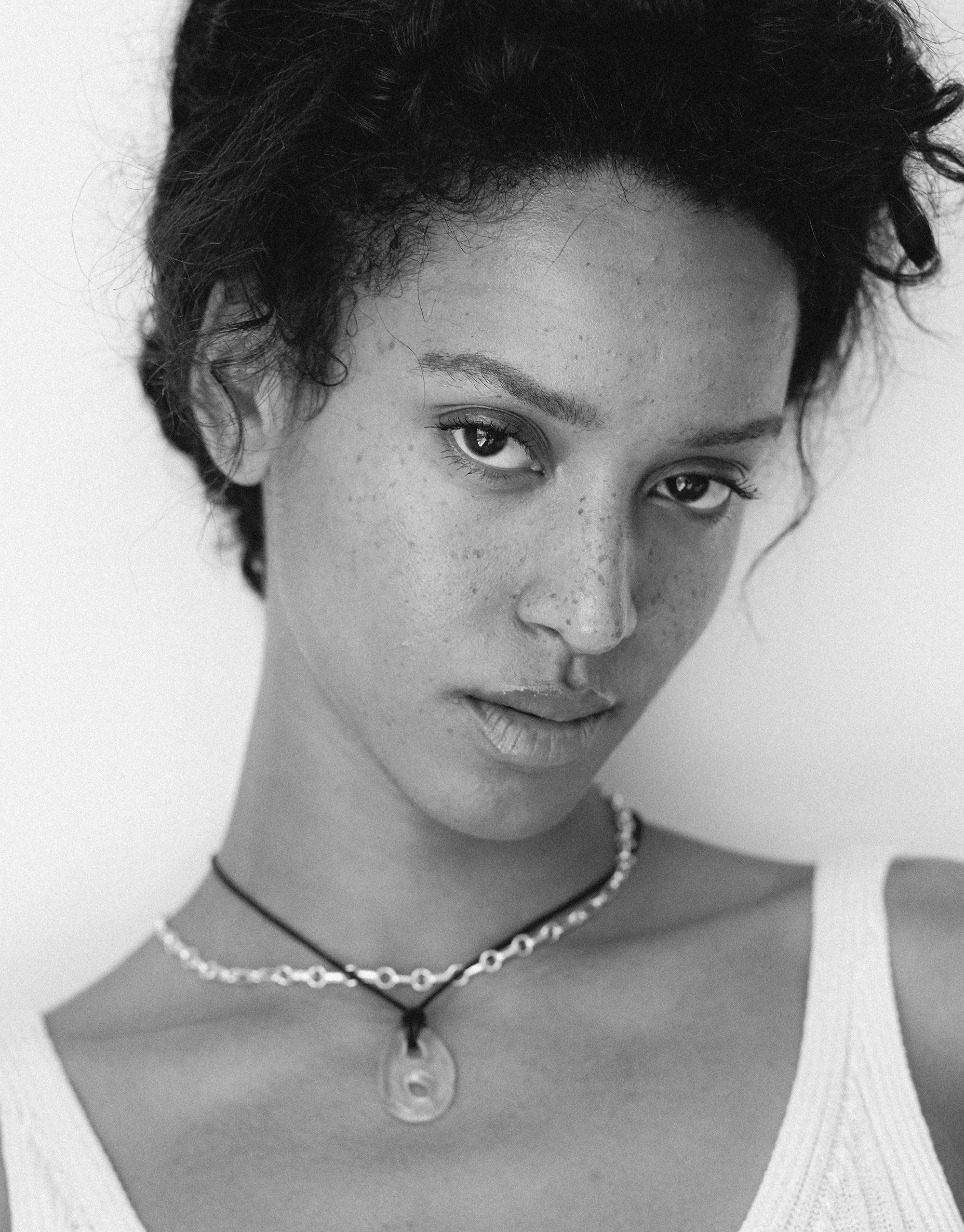 Black and white close-up portrait showcasing the Sculptural Small Charm Necklace | B. Delicate choker-style necklace with handcrafted charm made from upcycled glass, highlighting sustainable jewelry design. Elegant and eco-friendly accessory by CLED.