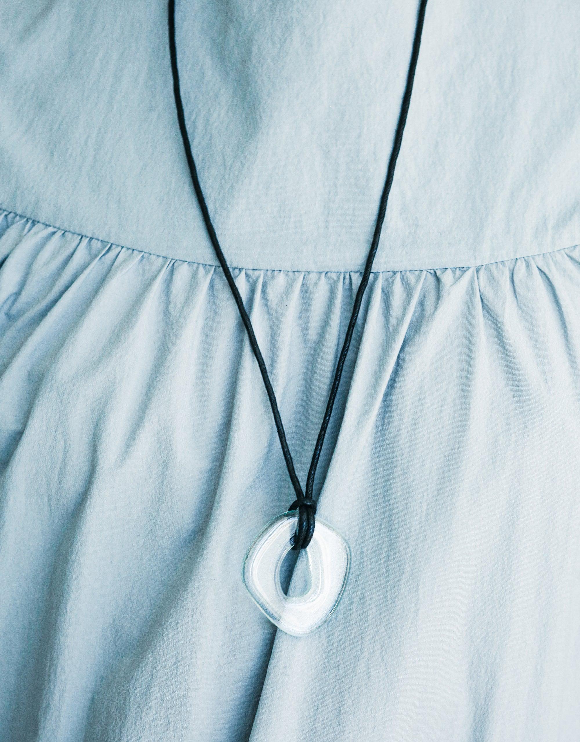 Sculptural Large Charm Necklace with upcycled glass pendant on black cord, displayed against light blue fabric. Eco-friendly, adjustable length, handmade jewelry. Sculptural Large Charm Necklace | A by CLED