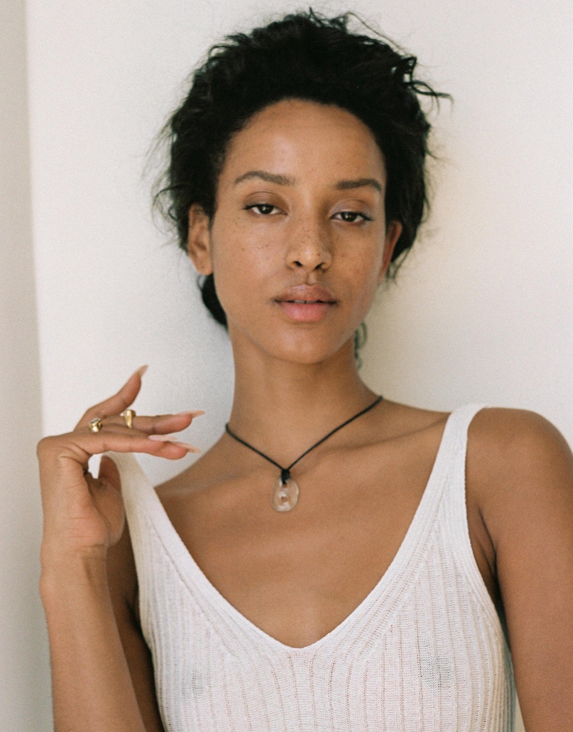Model wearing Sculptural Small Charm Necklace | B, featuring a delicate glass charm on a black cotton cord. Eco-friendly jewelry made from upcycled window glass, handcrafted in Los Angeles. Sustainable and stylish accessory by CLED.