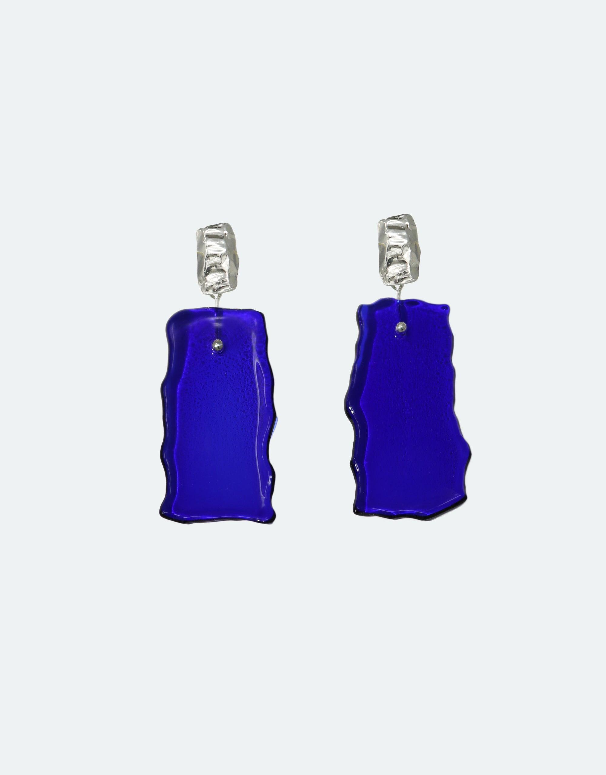 Afloat Earrings featuring vibrant blue hand-formed eco gem pendants made from repurposed glass bottles, suspended from textured silver hooks. Elegant and sustainable jewelry inspired by melting glaciers, part of the Floating Glacier Collection. CLED