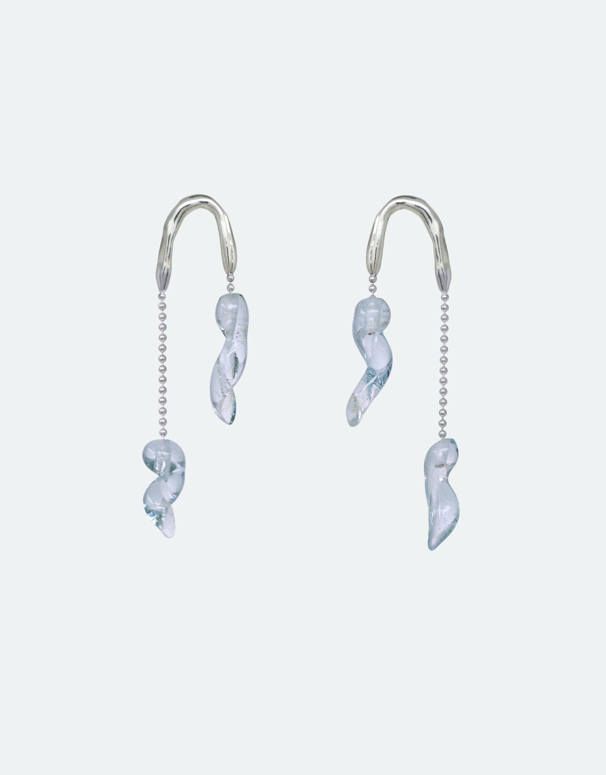 Asymmetrical silver earrings with delicate sky blue glass icicle-inspired pendants, reflecting climate change awareness. Handcrafted eco-friendly jewelry featuring curved shapes and beaded chains. Crystal Drops Earrings by CLED.