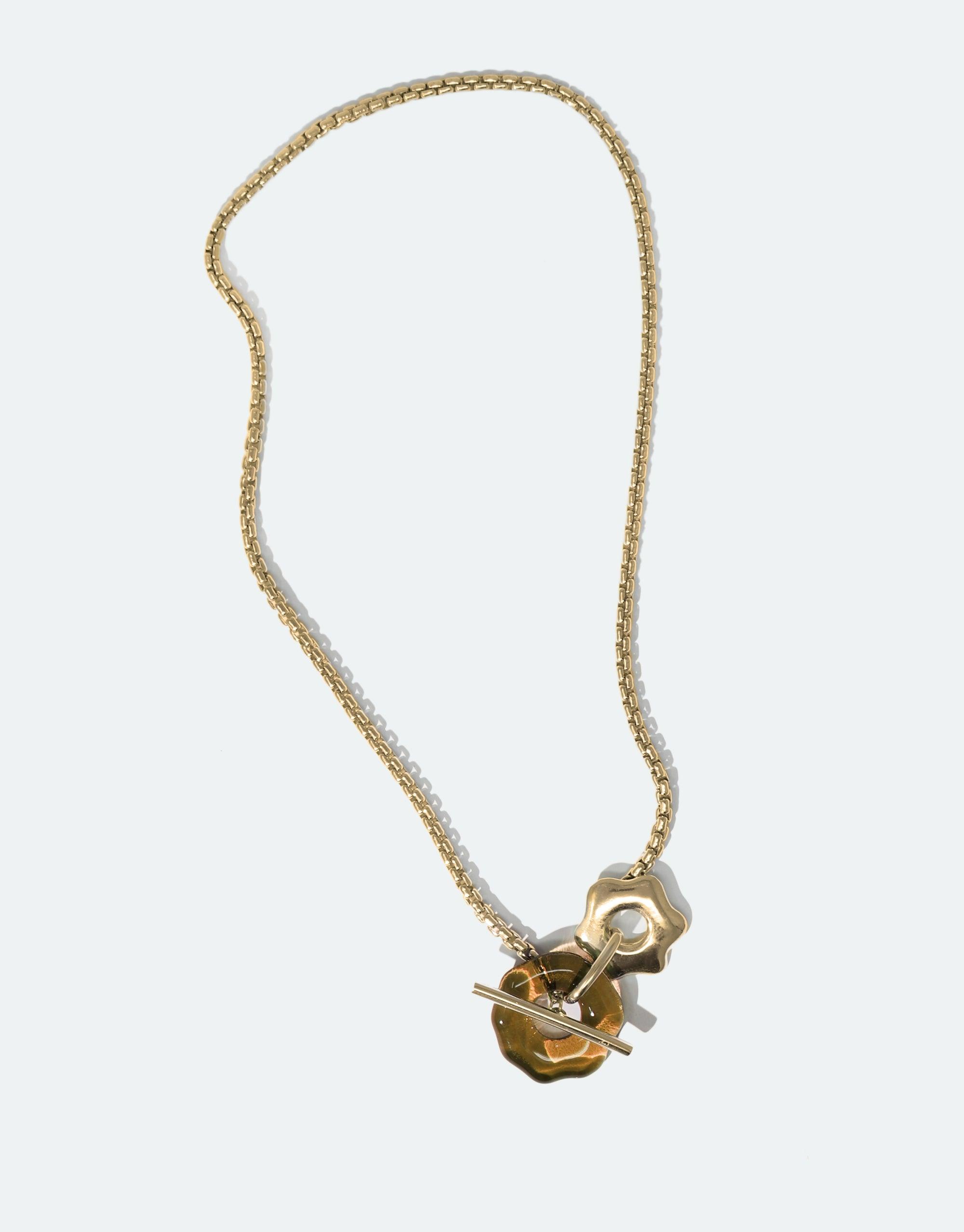 Elegant gold-tone necklace with toggle closure and abstract pendant inspired by mountain avens flower, part of the Floating Glacier Collection. Versatile design for climate change awareness. Avens Toggle Necklace by CLED.