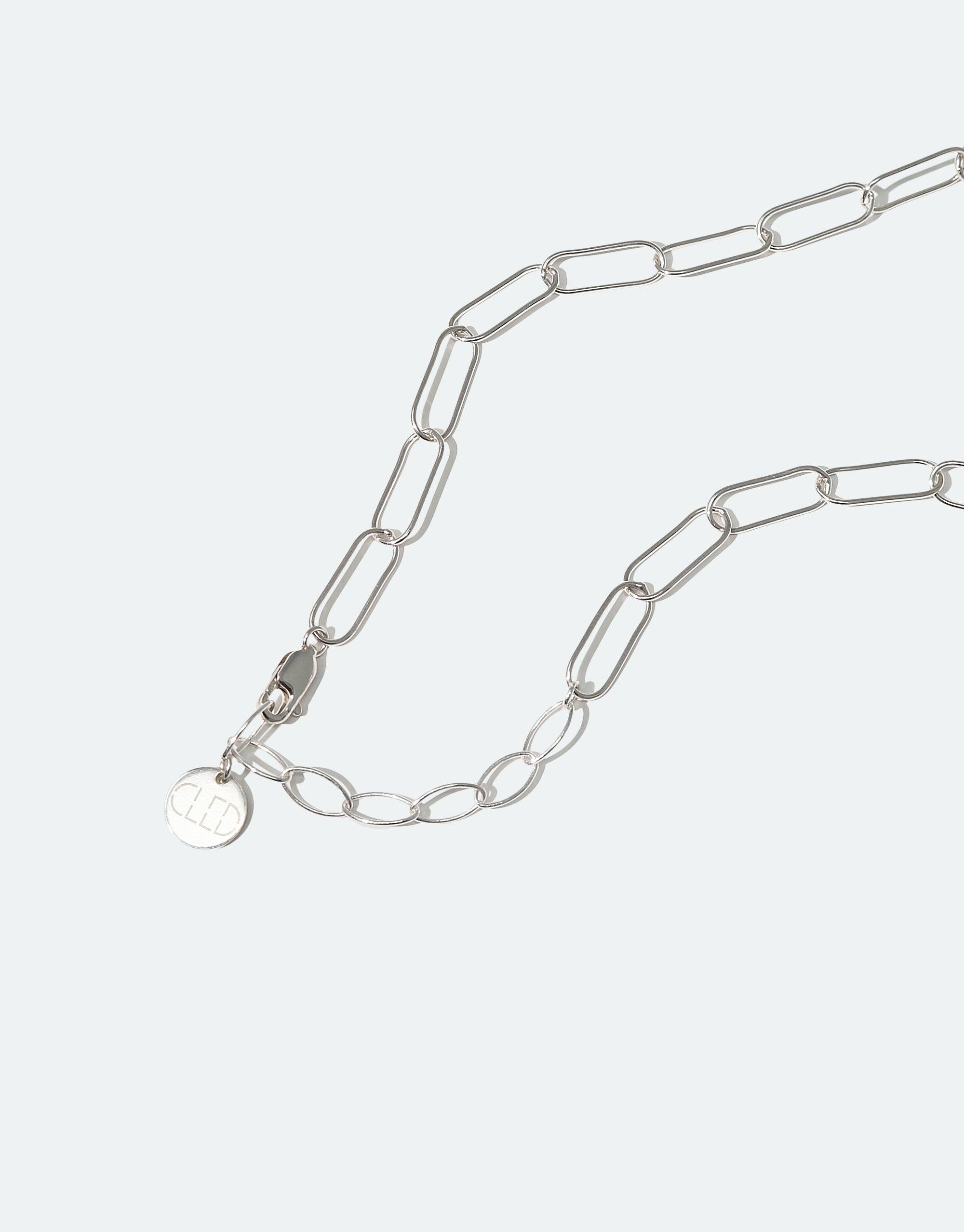 The Day Loop Necklace features a silver oval chain with a round tag, showcasing CLED's eco-conscious design with hand-formed Eco Gem from repurposed glass, emphasizing minimalist elegance.