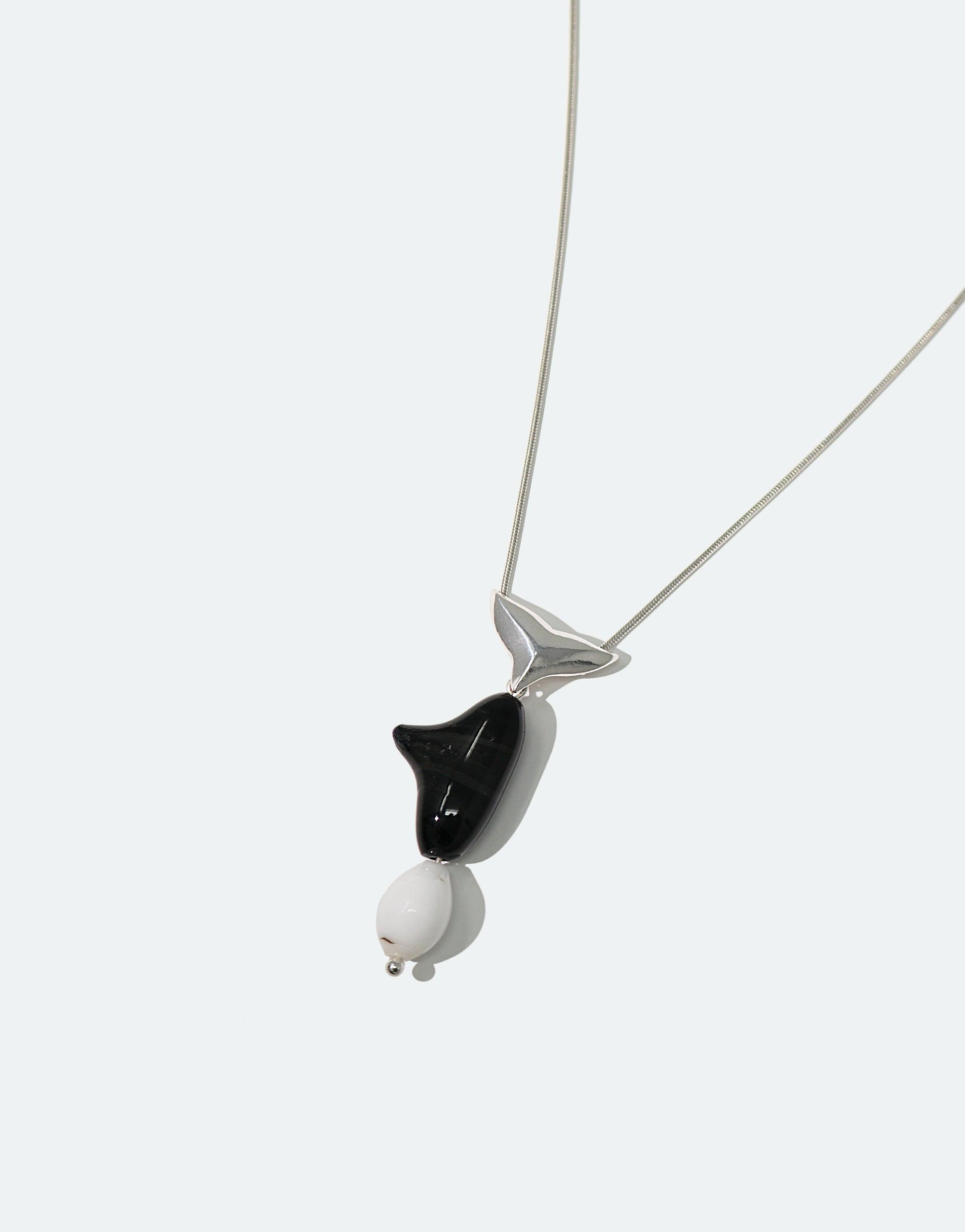 Orca Necklace featuring a stylized black and white pendant resembling an orca whale, crafted from eco-friendly repurposed glass, suspended on a delicate silver chain. Handmade sustainable jewelry from the Floating Glacier Collection by CLED