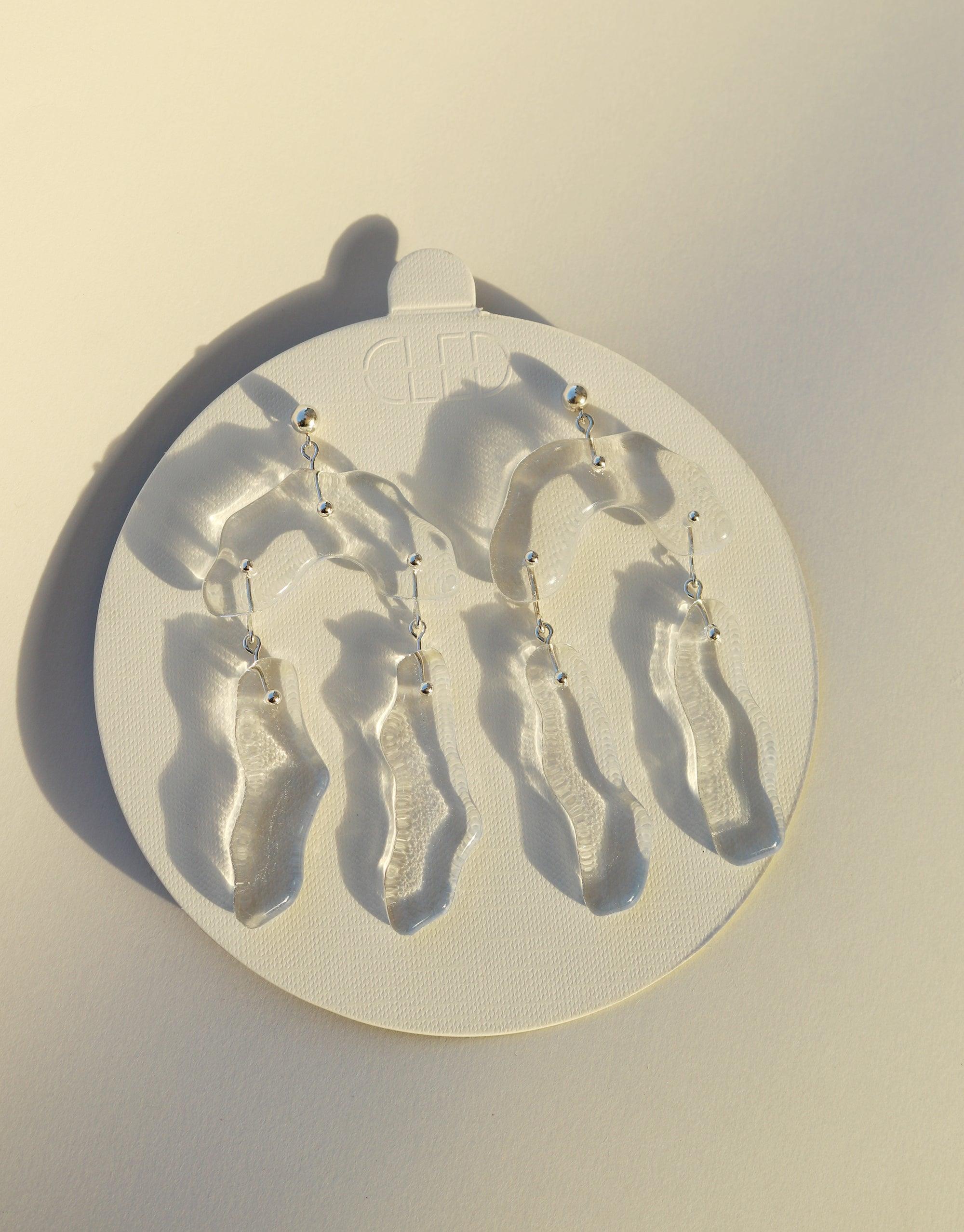 Handcrafted Rock Dangling Earrings featuring abstract, molten glass forms inspired by canyon terrain. Eco-friendly design with repurposed glass bottle charms. Unique, eye-catching jewelry piece showcasing dynamic movement and natural aesthetics. Rock Dangling Earrings by CLED.