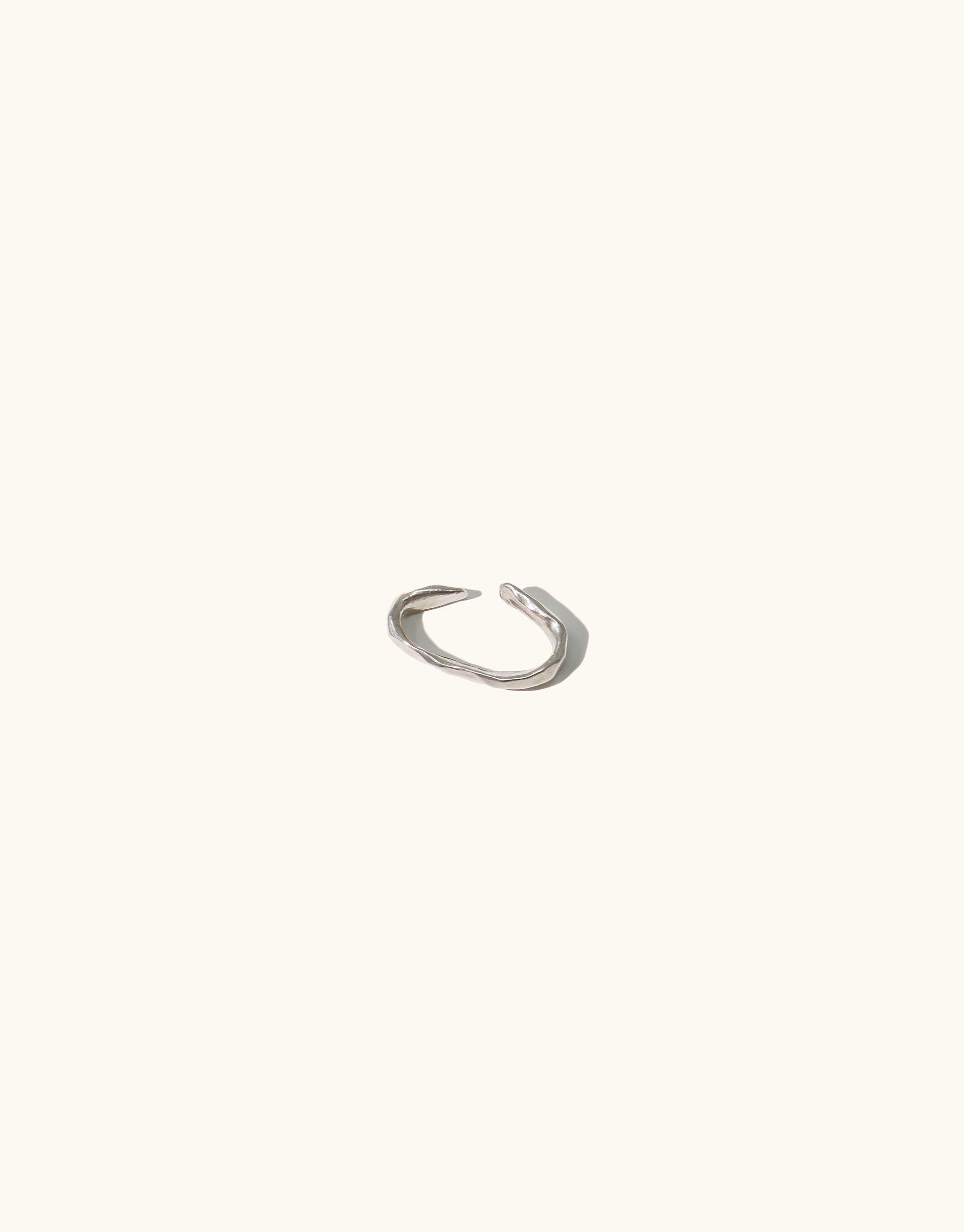 Sleek silver ear cuff with minimalist design, inspired by canyon terrain. Handcrafted abstract molten form, perfect for solo wear or pairing. Rock Ear Cuff Single from Terrain Collection, showcasing LA-made artisanal jewelry. CLED