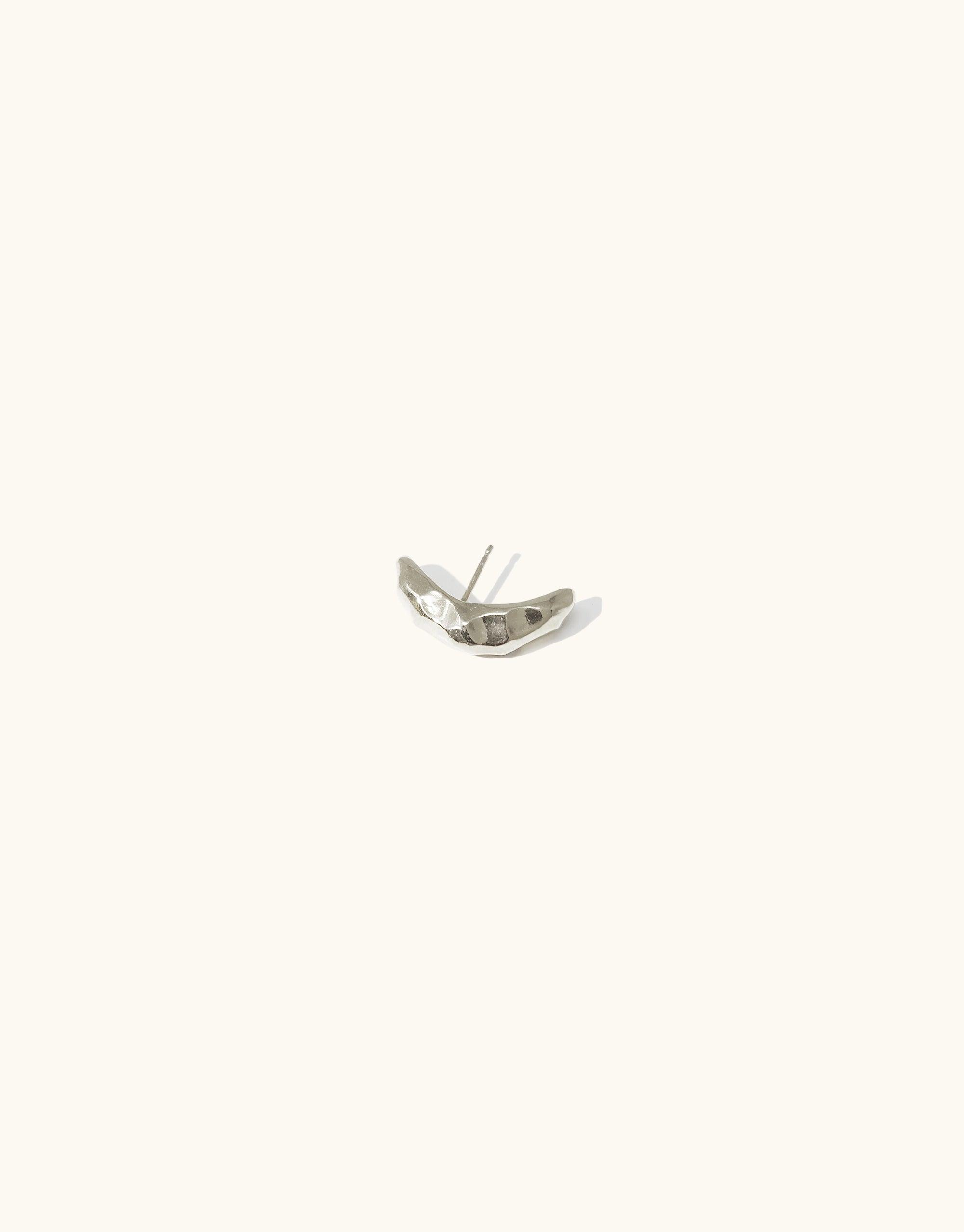Rock Stud Earrings: Sleek silver curved stud earring with textured surface, inspired by canyon terrain. Handcrafted piece from the Terrain Collection, showcasing abstract molten forms. Versatile accessory for day-to-night wear. Available in sterling silver or gold vermeil. CLED