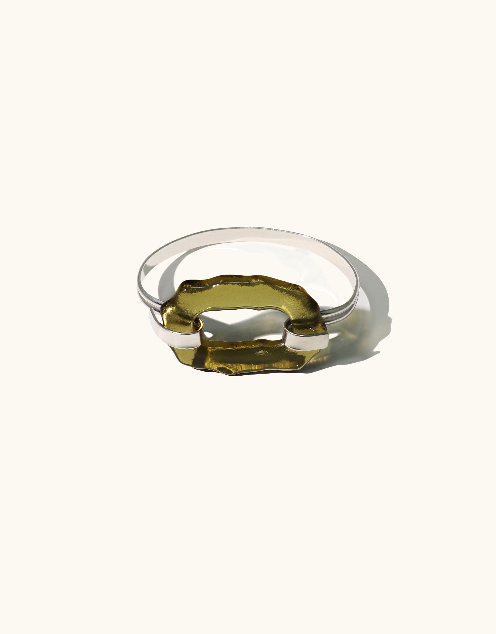 Canyon Hook Bracelet featuring a unique olive-green glass element set in a sleek silver band. Handcrafted eco-friendly jewelry inspired by canyon terrain. Elegant and versatile design for everyday or dressy wear. Sustainable luxury accessory by CLED.