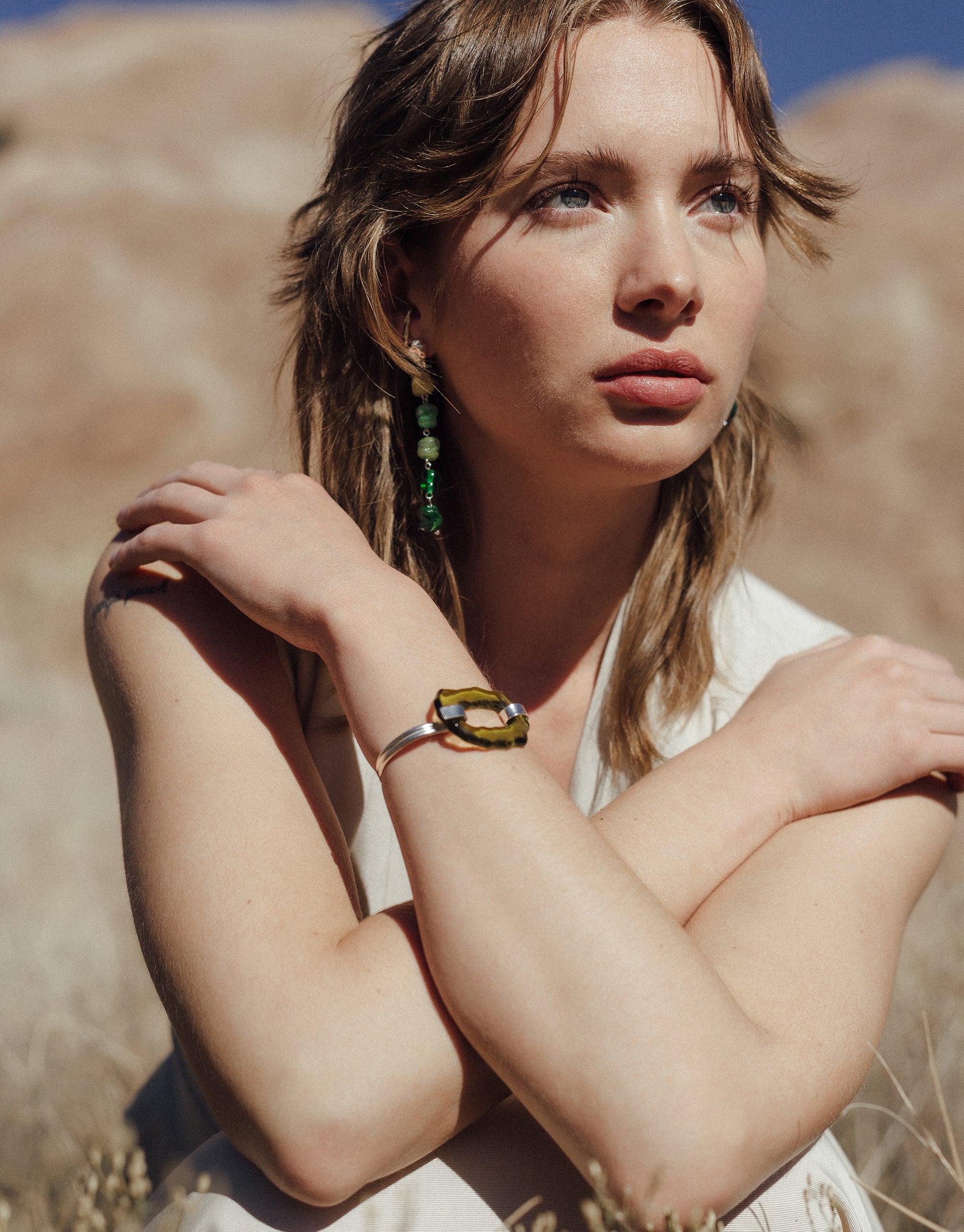 Model wearing Shades of Nature | Forest Earrings, long green eco-glass earrings inspired by canyon terrain, showcasing layered abstract forms against outdoor background. Handcrafted sustainable jewelry by CLED.