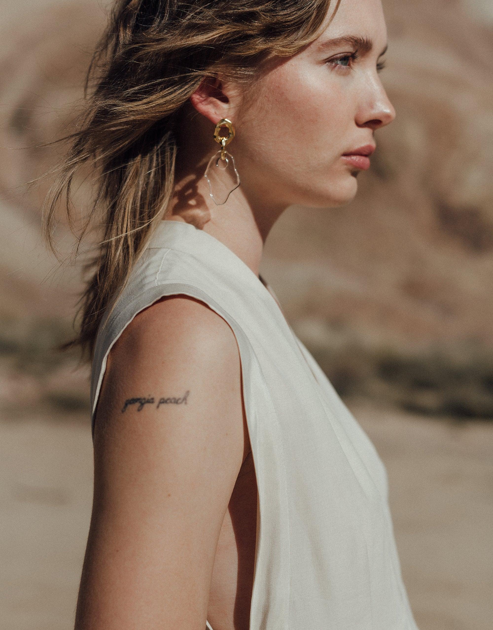 Side profile of a woman wearing Canyon Earrings, showcasing the organic, abstract design inspired by canyon terrain. The earrings feature eco-friendly glass and metal elements, reflecting CLED's sustainable approach to jewelry craftsmanship. Canyon Earrings by CLED.