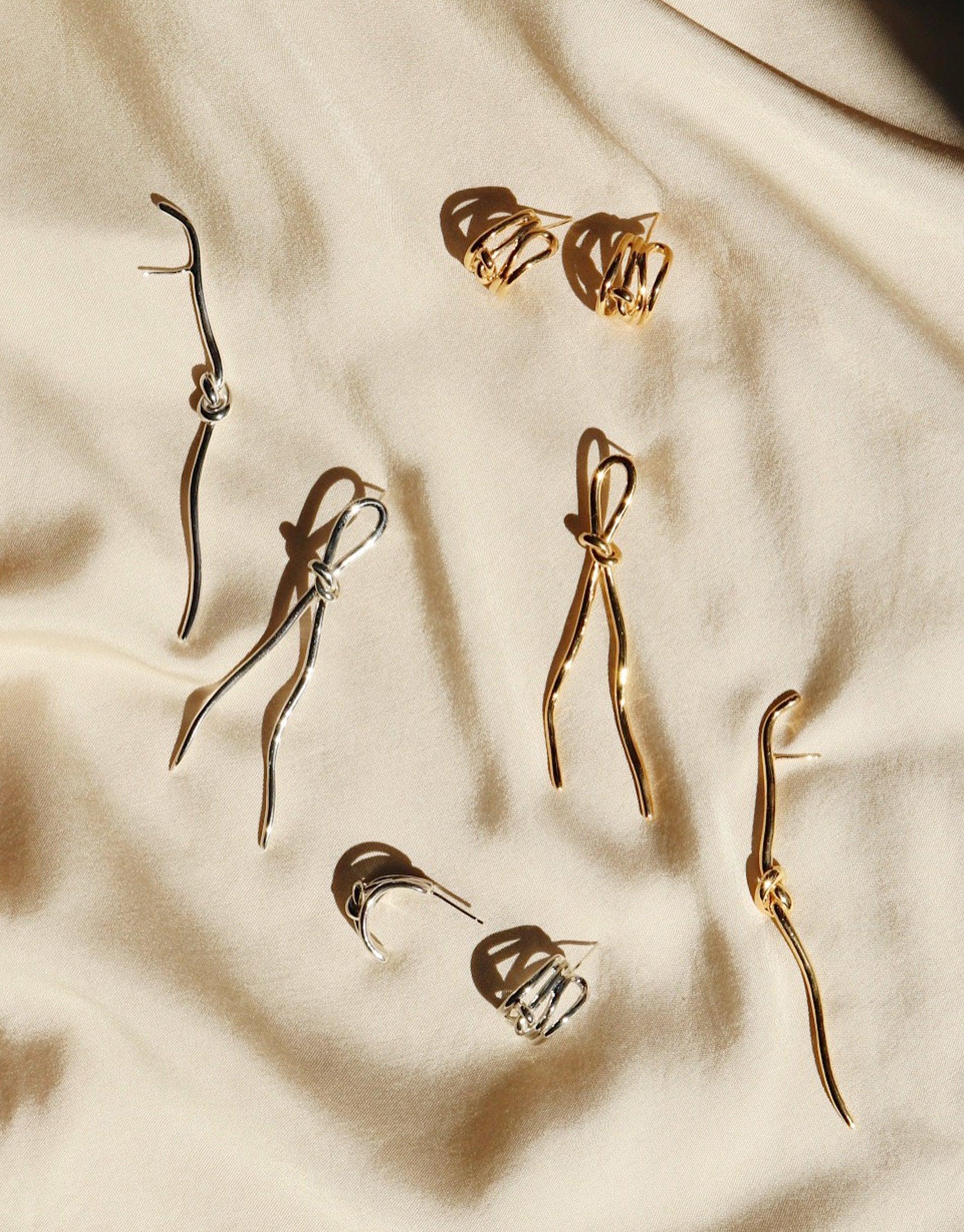 Elegant Rope Hoop Earrings displayed on cream fabric, showcasing various styles of minimalist gold and silver earrings inspired by canyon terrain. Abstract molten forms and curved designs reflect the Terrain Collection's unique aesthetic. Handmade in Los Angeles. CLED Rope Hoop Earrings.