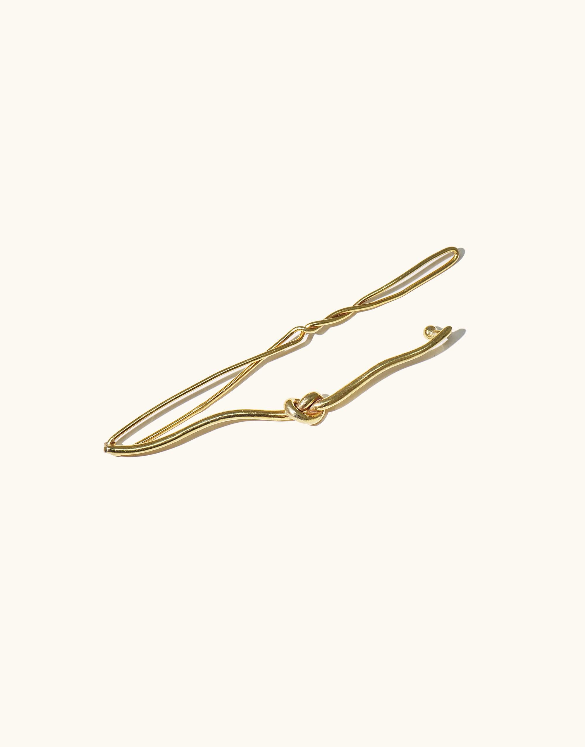 Elegant gold-toned Single Rope Hair Barrette with twisted design, inspired by canyon terrain. Handcrafted 3.5-inch hair accessory featuring smooth curves and a delicate knot detail. Stylish and minimalist hair clip for a sophisticated look. Part of the Terrain Collection by CLED.