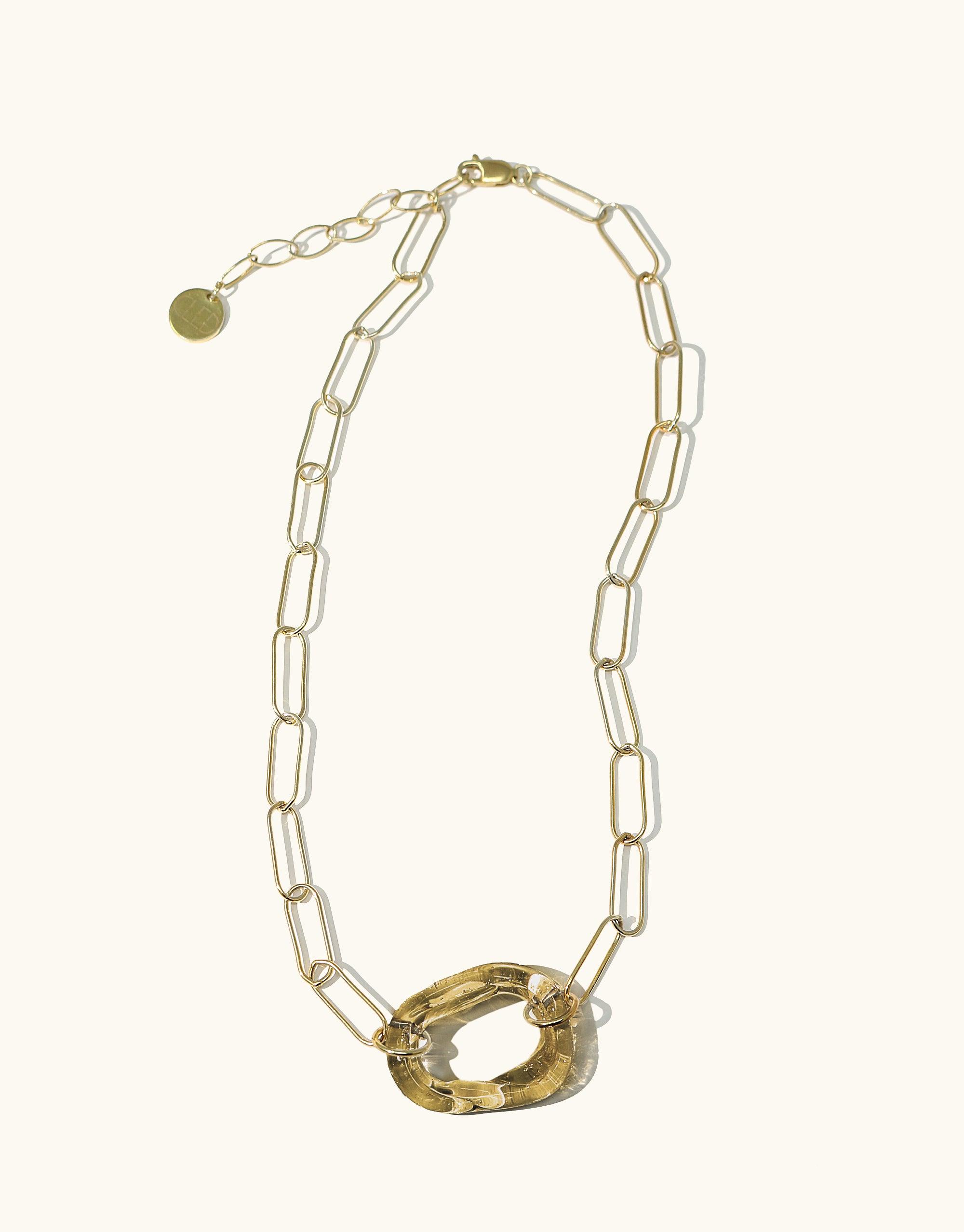 The Day Loop Necklace showcases a long gold chain with oval links, featuring a distinctive round pendant, embodying CLED's eco-conscious design crafted from repurposed glass, highlighting minimal elegance.