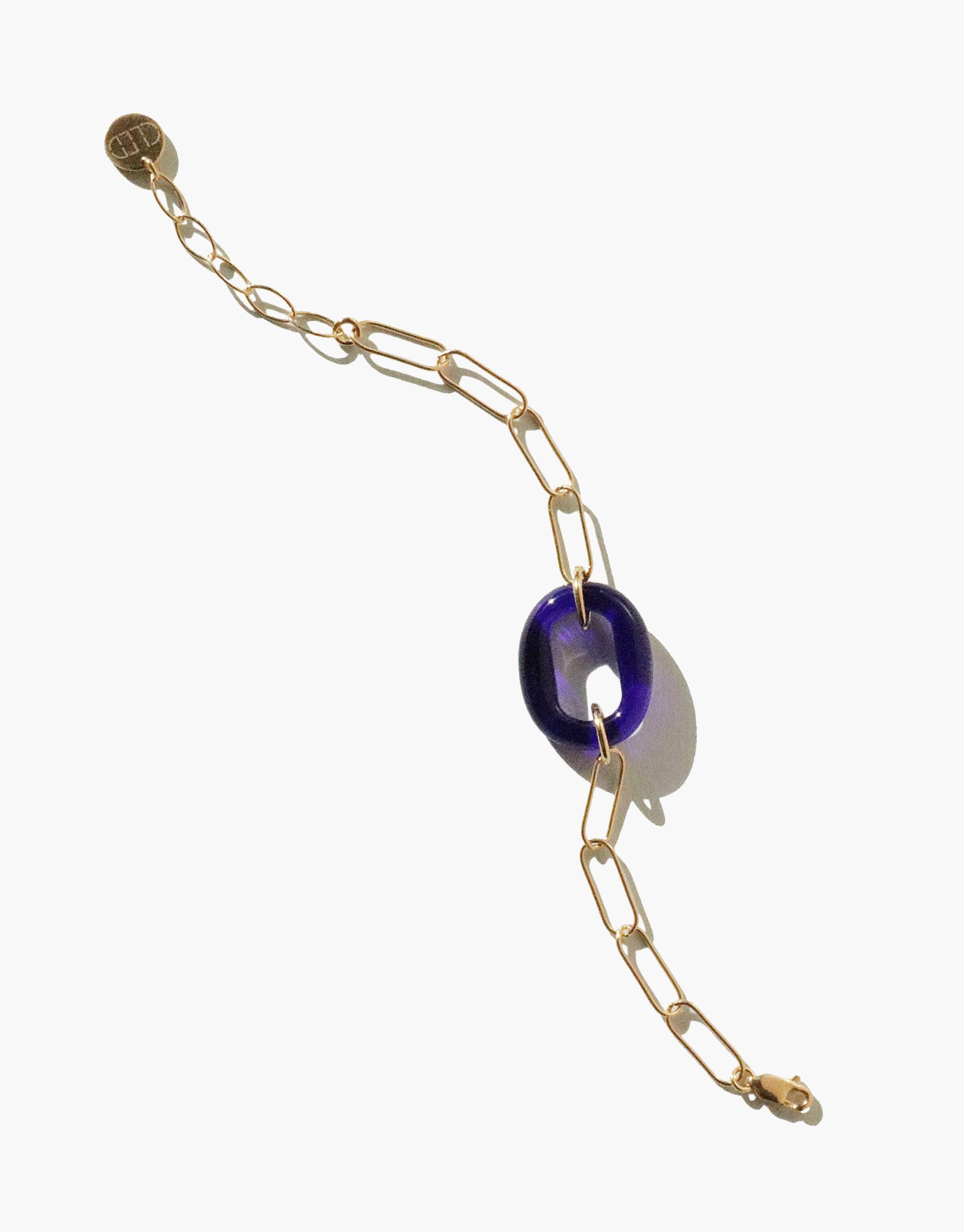 The Day Loop Bracelet features a blue glass bead on a gold oval chain, showcasing a minimalistic design, hand-formed from repurposed glass, embodying eco-conscious elegance.