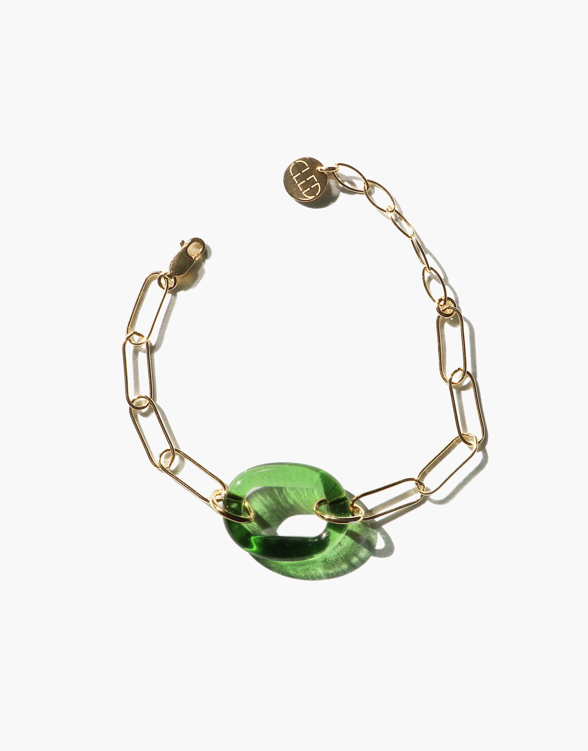 The Day Loop Bracelet features a gold oval chain with a green Eco Gem stone, highlighting CLED's eco-conscious design, handcrafted from repurposed glass for a minimalistic statement piece.