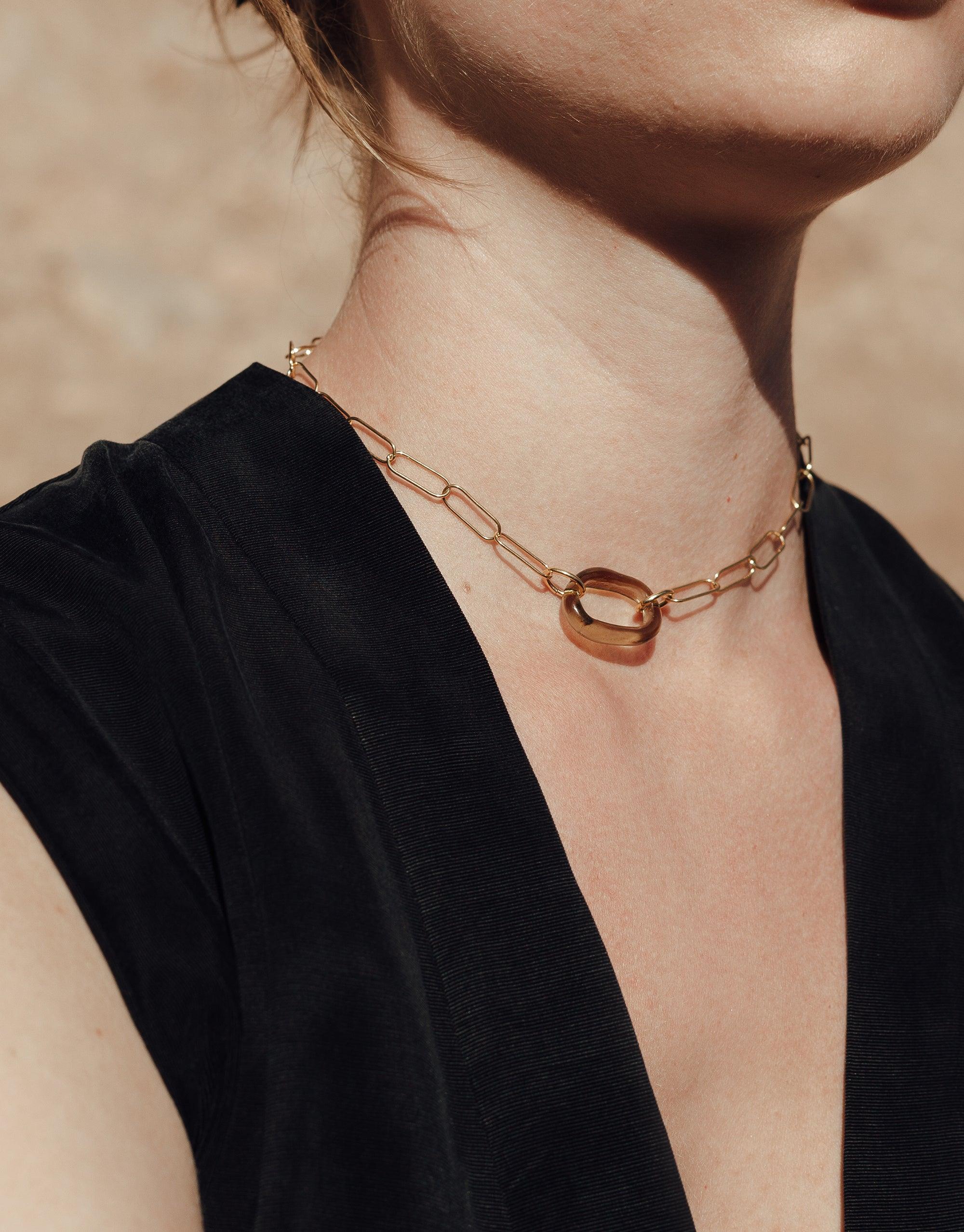 The Day Loop Necklace elegantly draped on a woman's neck, featuring a minimal oval chain design, embodying CLED's eco-conscious craftsmanship with repurposed glass Eco Gems.