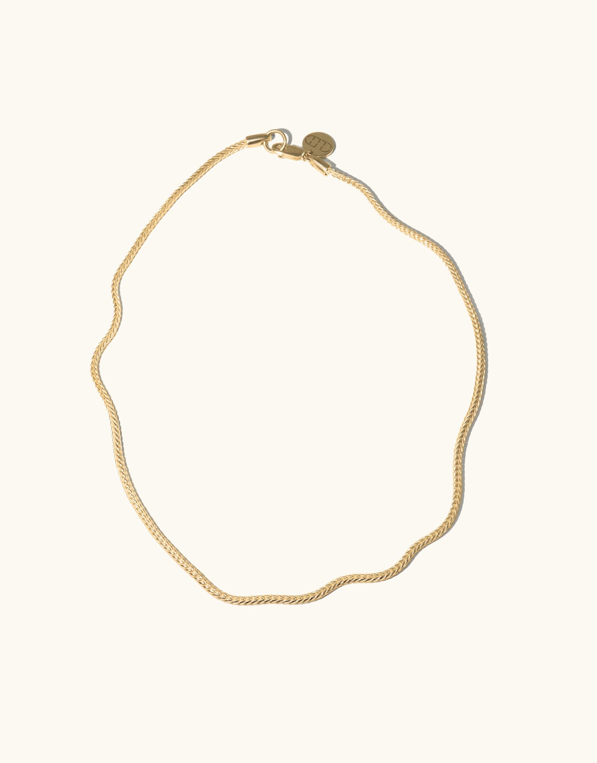 A gold chain necklace displayed against a clean white background, highlighting its shine and intricate woven chain design.