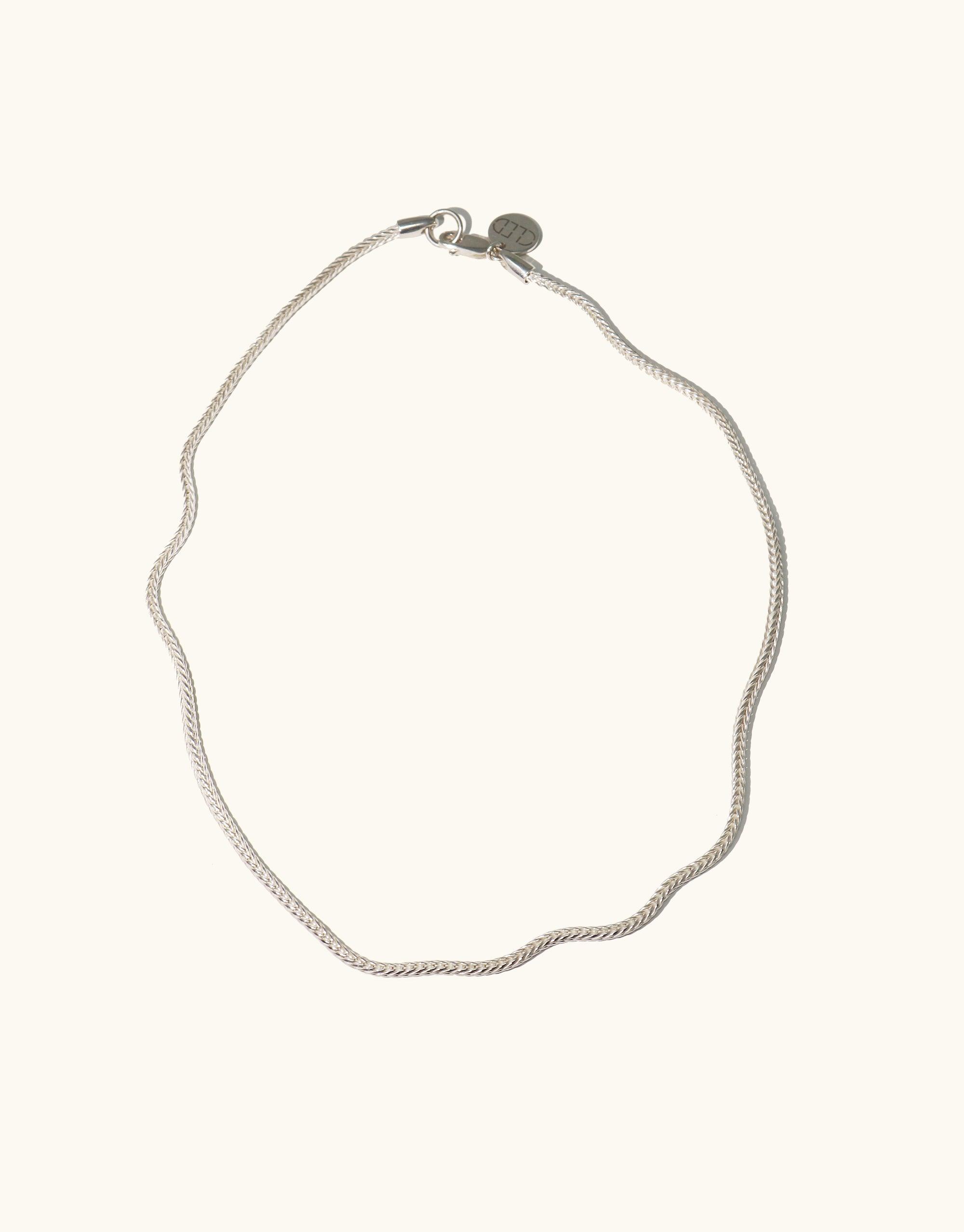 A silver chain necklace displayed against a clean white background, highlighting its shine and intricate woven chain design.