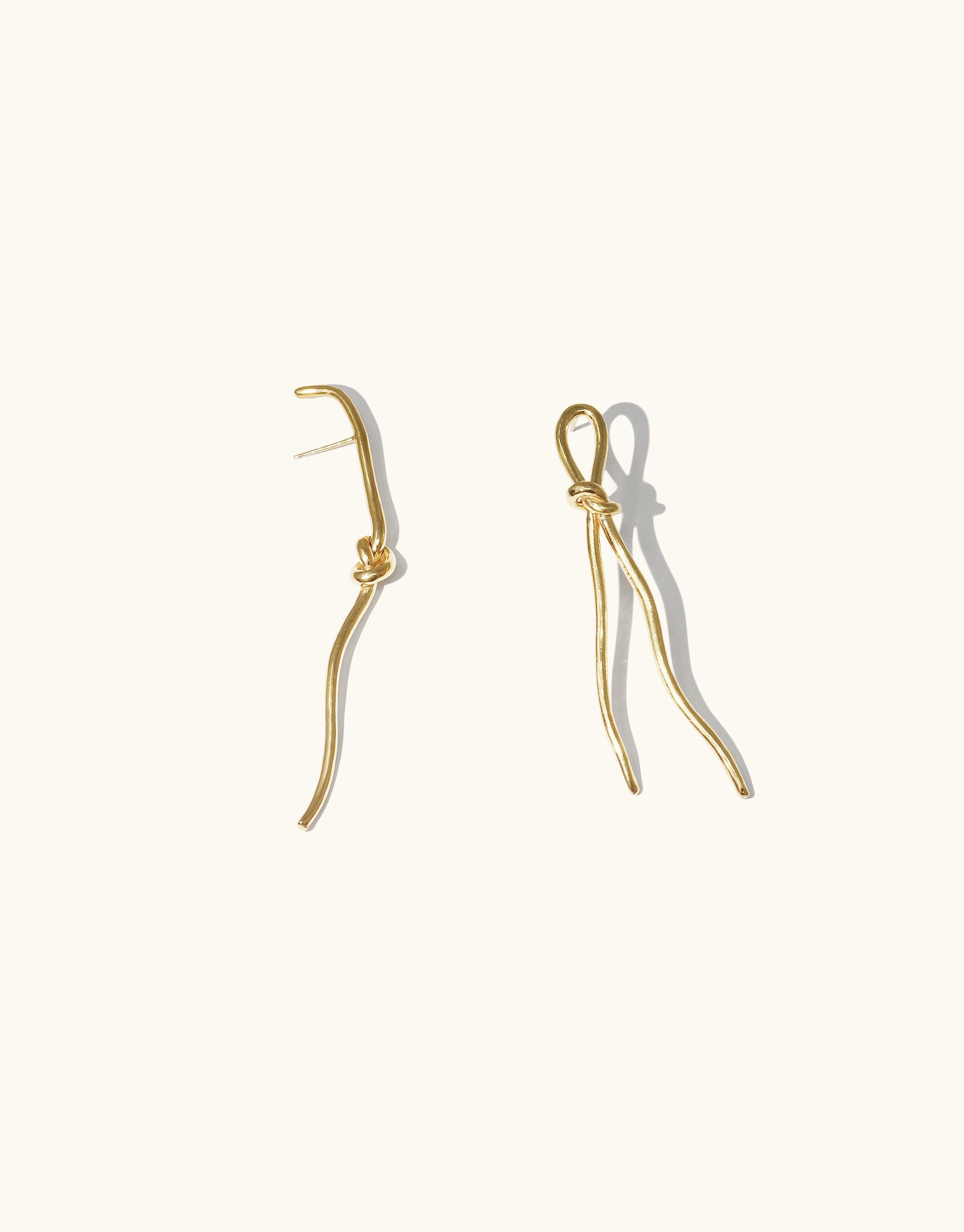 Elegant gold vermeil Rope Earrings from the Terrain Collection, featuring unique canyon-inspired designs. Two distinct rope shapes, one with a knot detail, create a stylish asymmetric look. Handcrafted in Los Angeles, these earrings showcase abstract molten forms reminiscent of canyon formations. CLED Rope Earrings.