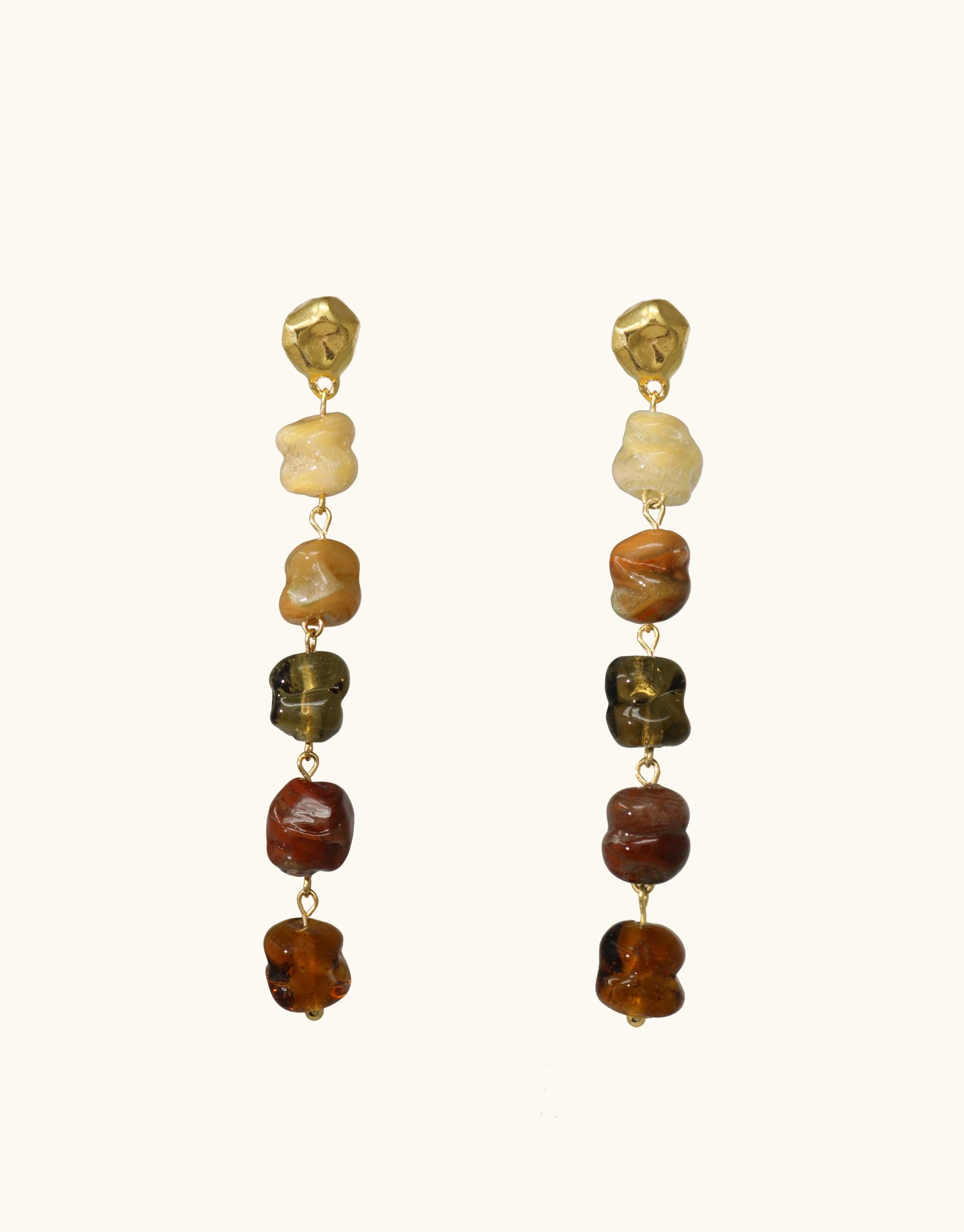 Dangling earrings featuring eco-friendly glass beads in earthy tones, inspired by canyon terrain. Long design with six irregular-shaped beads in gradient colors from light to dark, connected by gold vermeil links. Handcrafted, sustainable jewelry showcasing natural beauty. Shades of Nature | Sandstone Earrings by CLED.