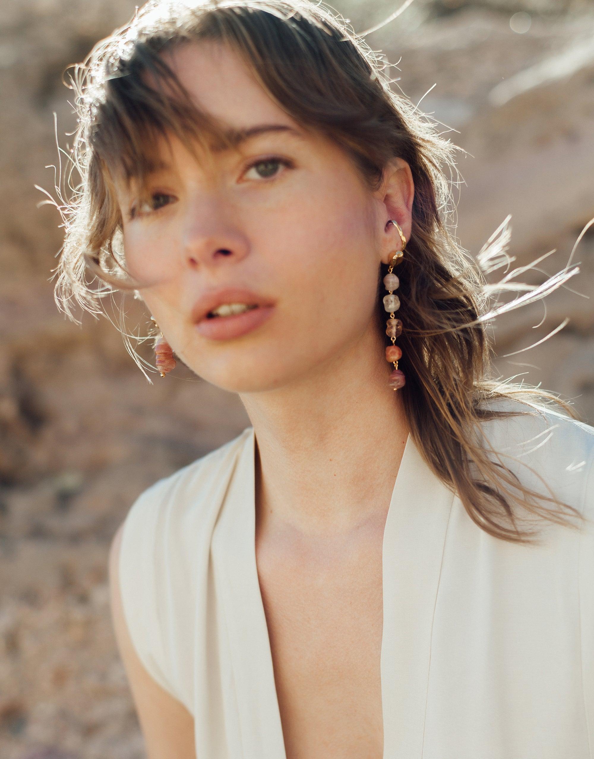 Model wearing white sleeveless top showcasing elegant earrings against desert backdrop, highlighting Rock Ear Cuff | Single from Terrain Collection. Handcrafted jewelry inspired by canyon formations, available in Sterling Silver or Gold Vermeil. Made-to-order by CLED.
