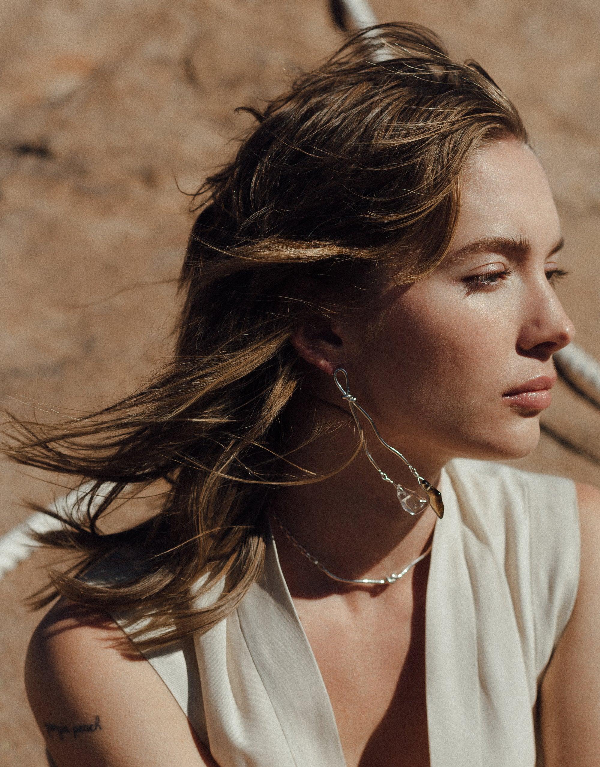 Model wearing Rope Drop Earrings, showcasing long, silver abstract designs inspired by canyon terrain and rock climbing ropes. Eco Gem drops add elegance to the handcrafted earrings. Part of the Terrain Collection by CLED, these Rope Drop Earrings blend sustainability with style.