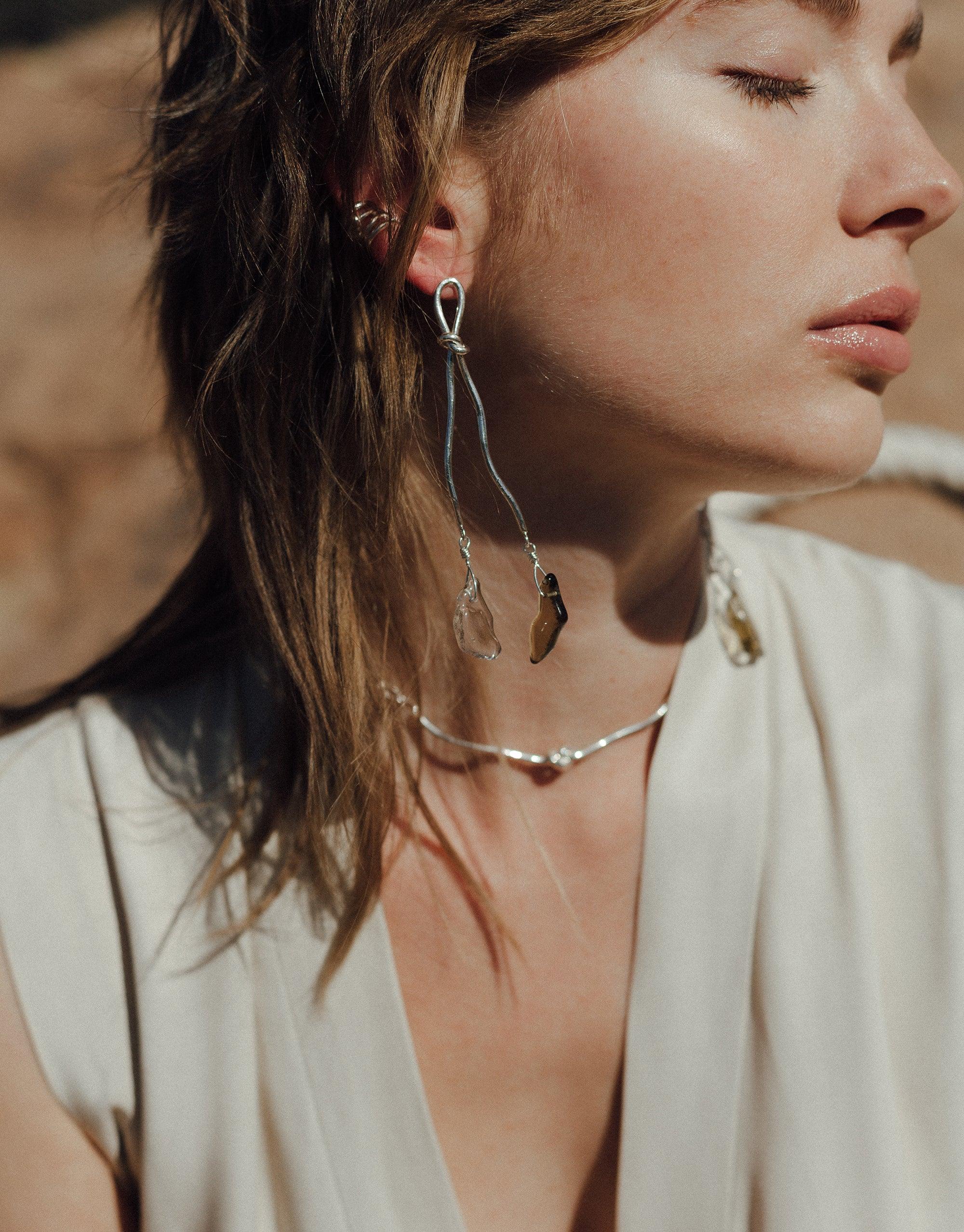 Close-up of a woman wearing delicate jewelry, including a rope ear cuff and dangling earrings, showcasing the Terrain Collection's canyon-inspired design. Elegant and minimalist aesthetic, perfect for the Rope Ear Cuff | Single by CLED.