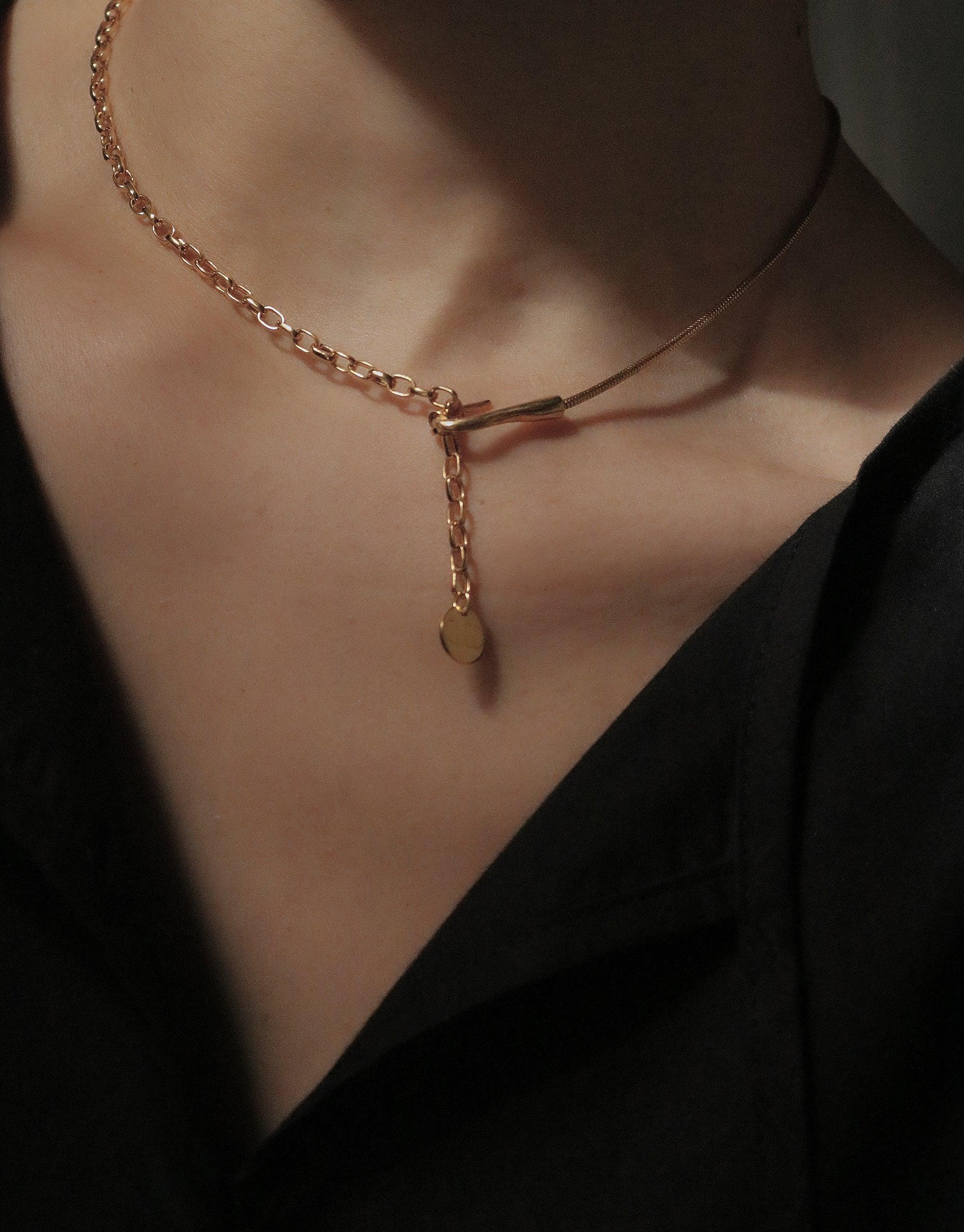Close-up of a delicate gold chain necklace with a unique hook design and pendant, worn on a person's neck against a dark background, showcasing the Rope Hook Necklace's versatile and elegant style. CLED Rope Hook Necklace.