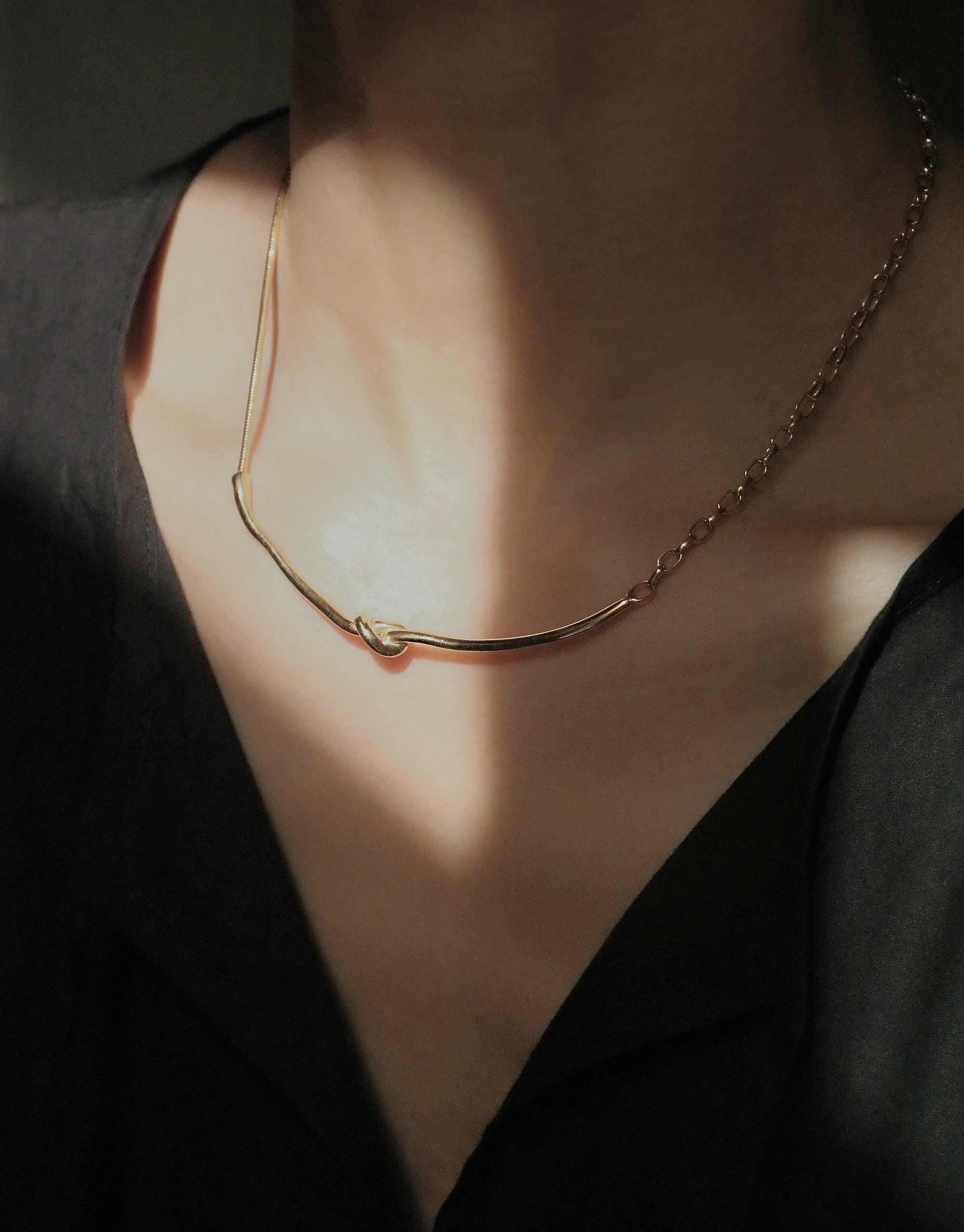 Elegant gold Rope Hook Necklace from the Terrain Collection, showcasing a unique curved design inspired by canyon formations. Versatile piece that can be worn in front or back, highlighting the neckline against soft skin. Handcrafted in Los Angeles by CLED.