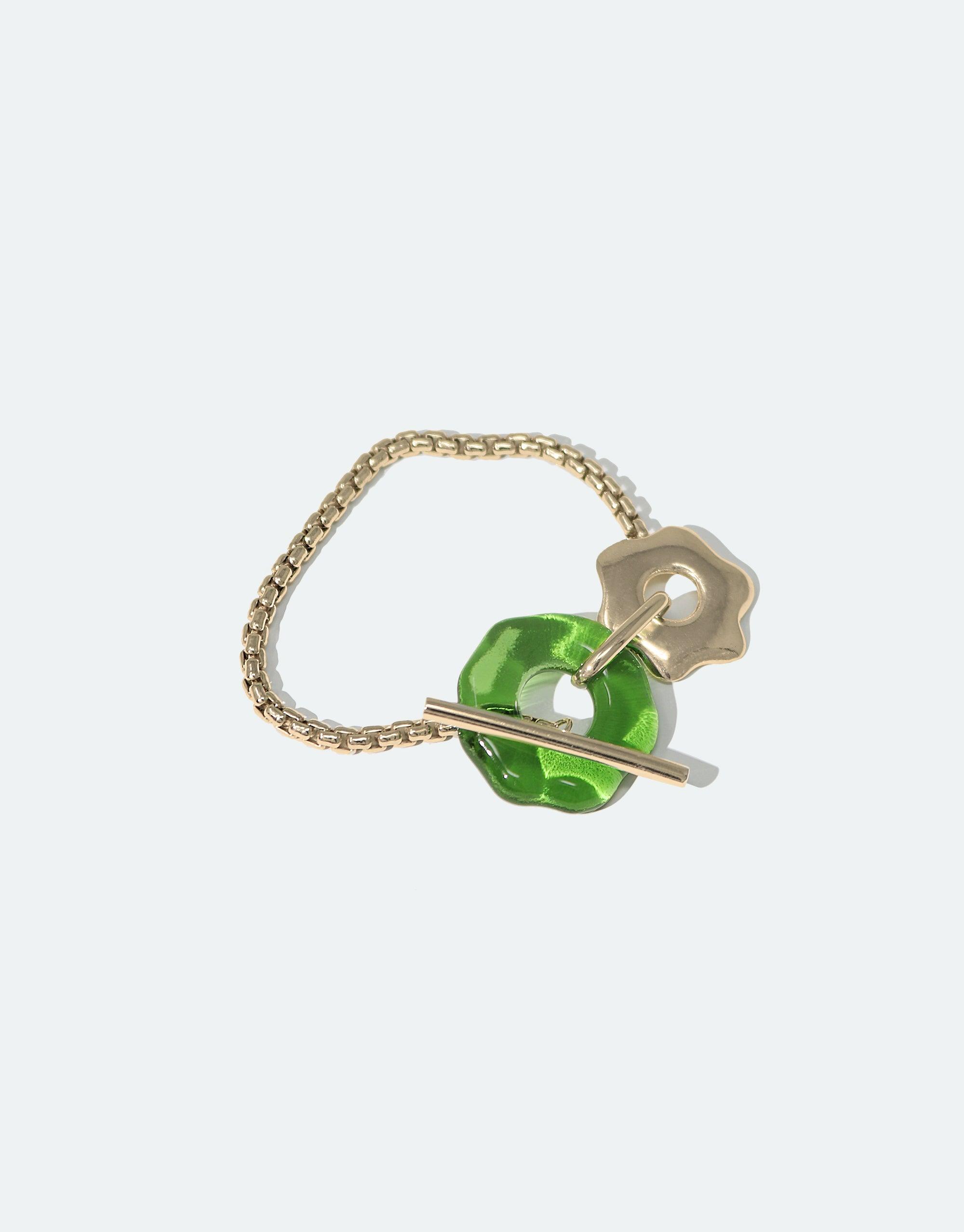 Avens Toggle Bracelet featuring gold chain, green eco gem toggle, and flower-inspired clasp. Elegant and eco-friendly design from Floating Glacier Collection. Handmade jewelry raising climate change awareness. CLED, Avens Toggle Bracelet.
