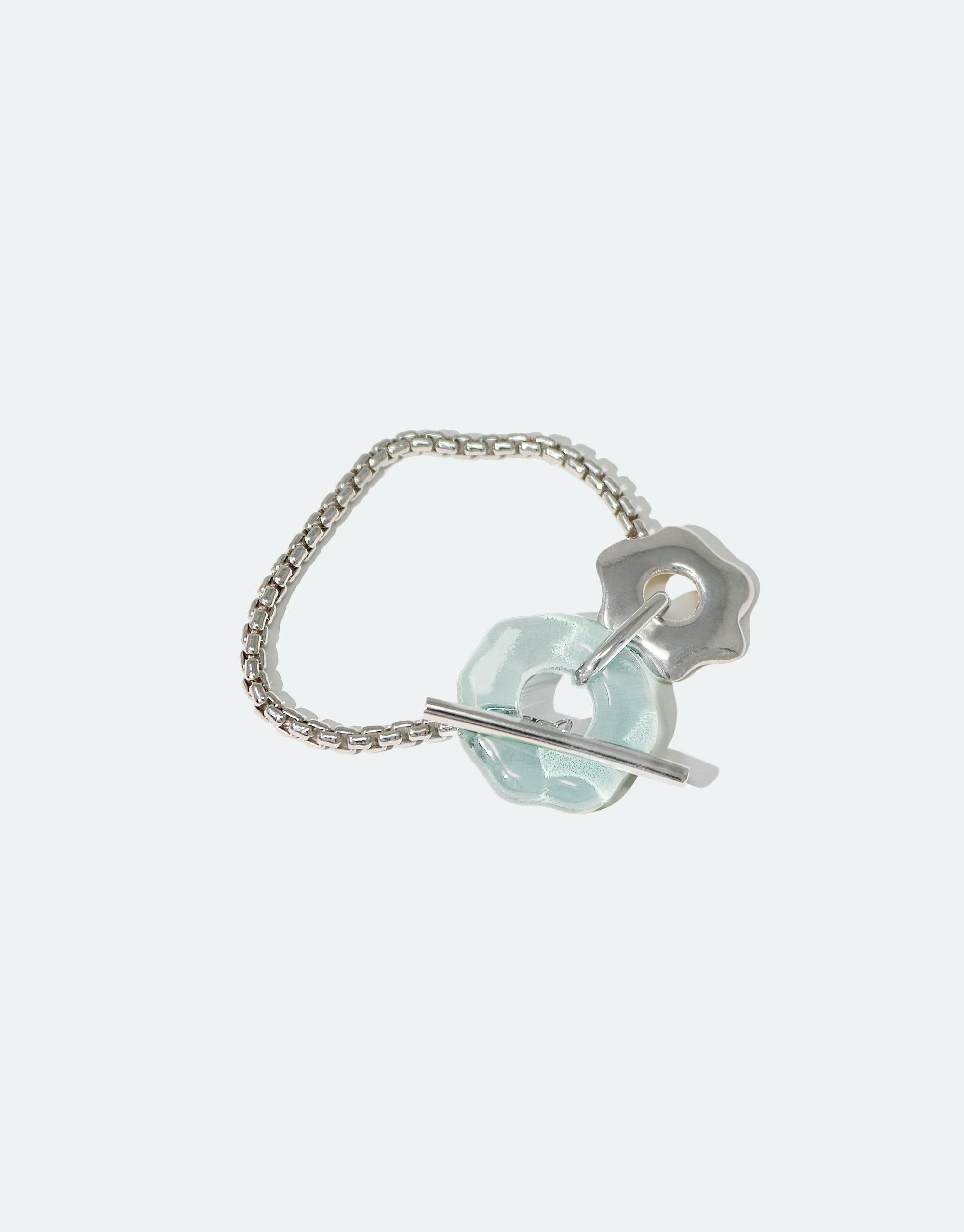 Avens Toggle Bracelet featuring a delicate silver chain with a unique flower-shaped toggle clasp and a pale blue eco-gem made from recycled glass, inspired by Arctic flora and climate awareness. Handcrafted sustainable jewelry by CLED.