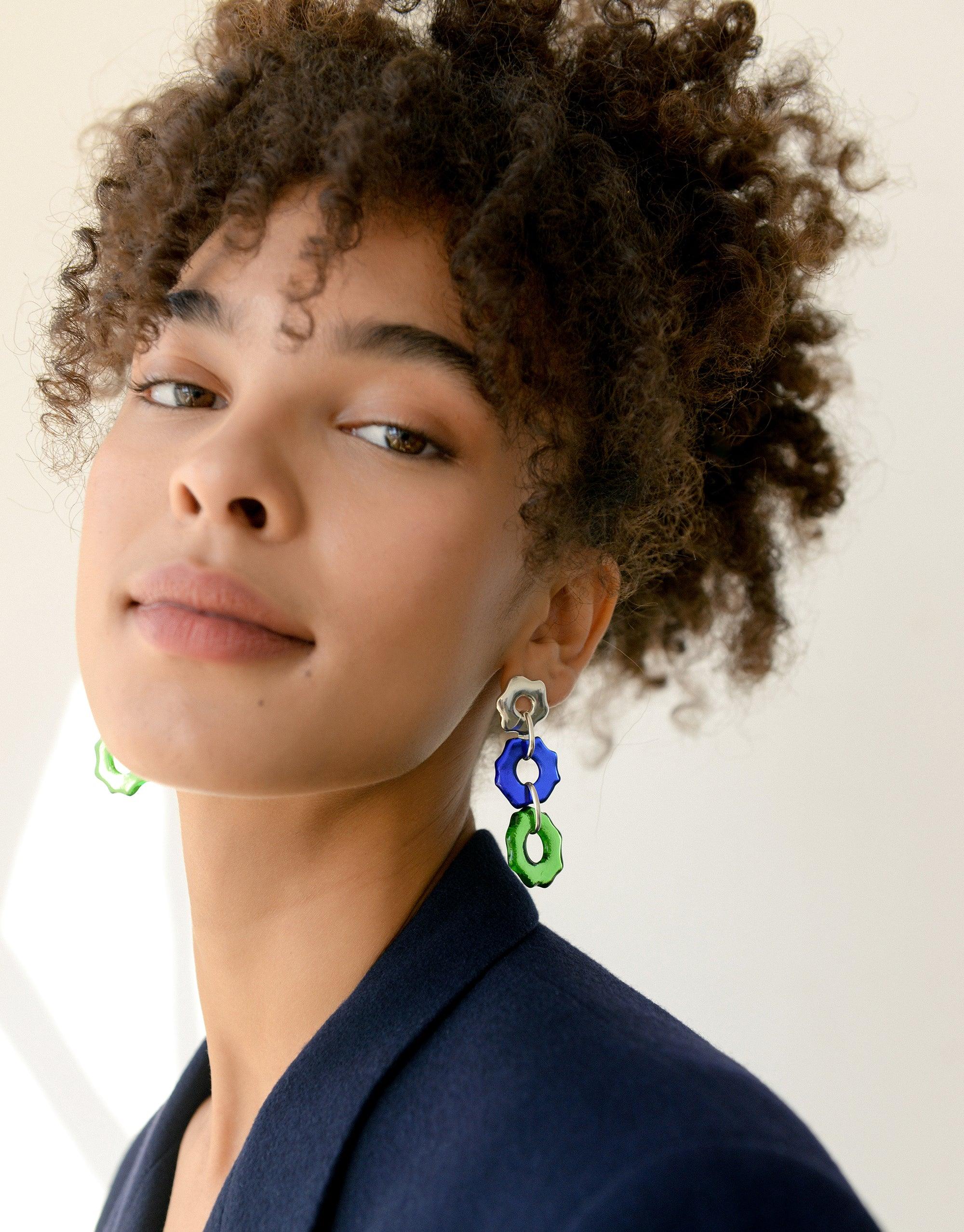 Close-up of model wearing Avens Earrings Trio featuring blue and green eco-friendly glass charms. Sustainable jewelry showcasing organic floral forms inspired by Arctic ecosystems. Handcrafted earrings by CLED.