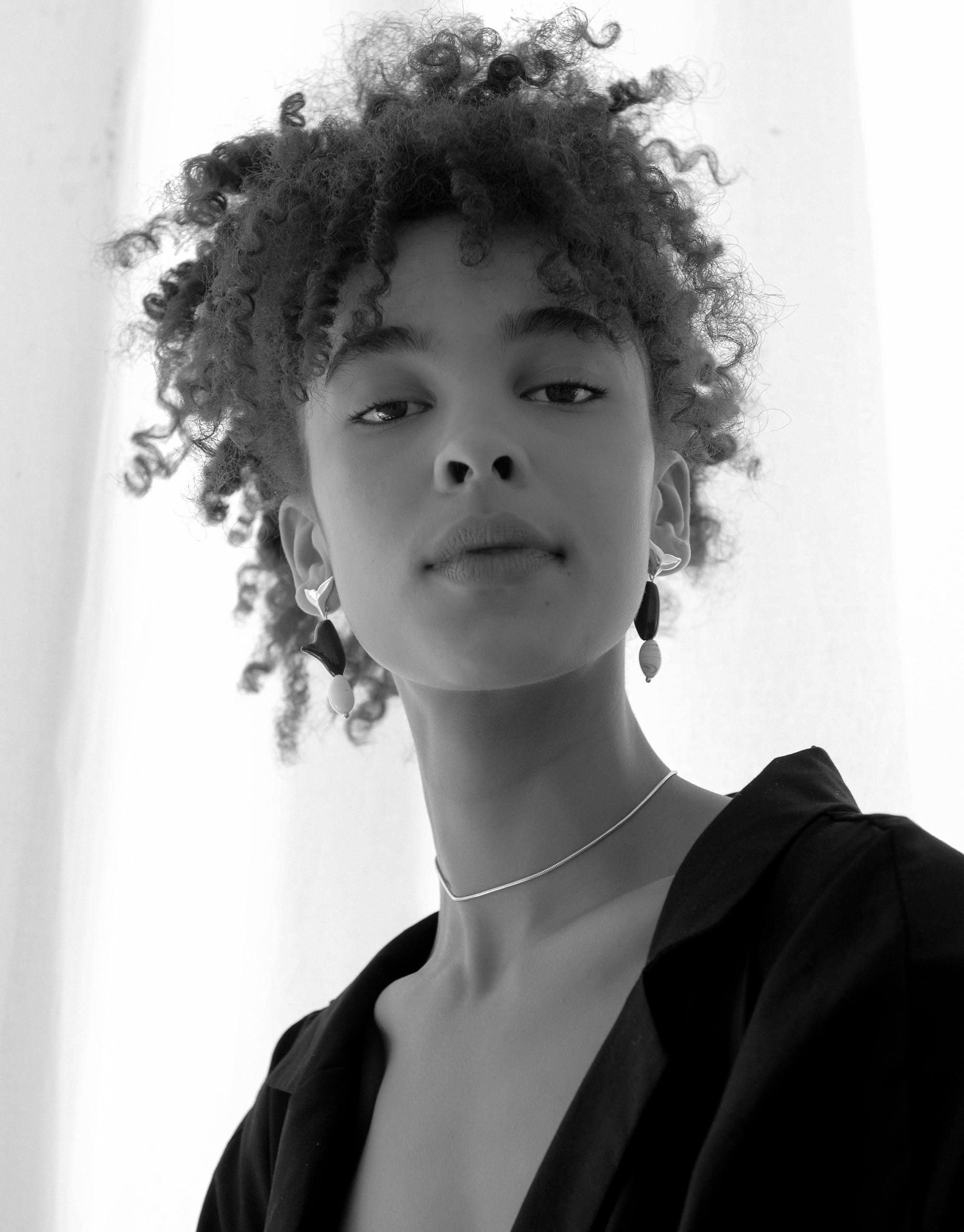 Model wearing Orca Earrings, part of the Floating Glacier Collection. Black and white portrait showcasing eco-friendly jewelry inspired by marine life. Handcrafted design highlights awareness for endangered species and climate change. Sustainable fashion by CLED.