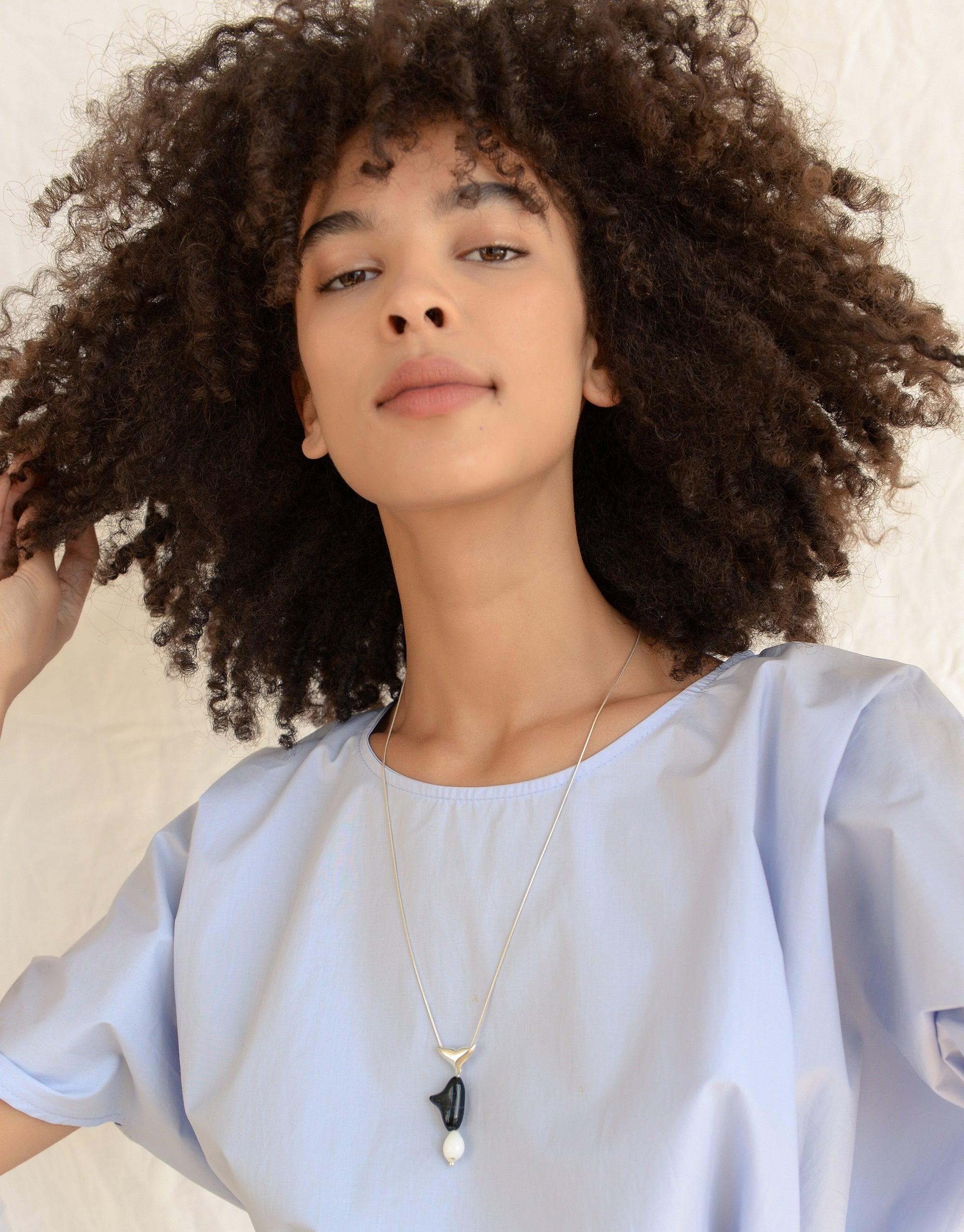Elegant model wearing Orca Necklace from Floating Glacier Collection, featuring eco-friendly glass pendant on delicate chain. Sustainable jewelry highlighting climate change awareness. Handmade in Los Angeles. Orca Necklace by CLED.