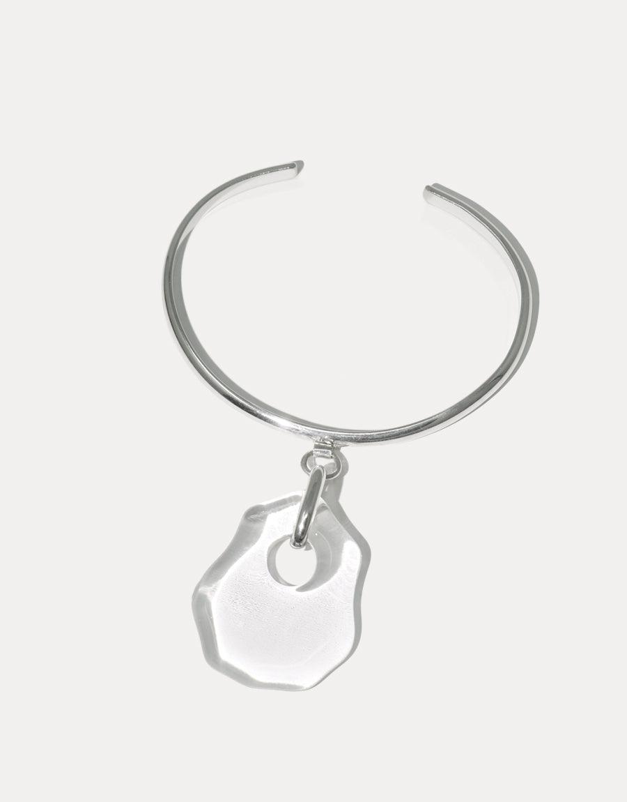 Elegant silver cuff bracelet with a unique, irregular-shaped glass pendant, inspired by coastal forms. Handcrafted Coastline Drop Bracelet featuring eco-friendly repurposed glass, showcasing sustainable luxury and artisanal craftsmanship. CLED Coastline Drop Bracelet.