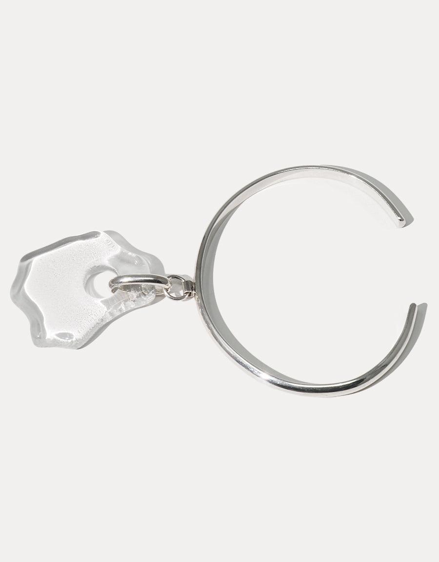 Sterling silver cuff bracelet with clear eco-friendly glass pendant, inspired by coastal shapes. Handcrafted Coastline Drop Bracelet featuring a curved design and transparent accent, showcasing sustainable luxury jewelry. CLED