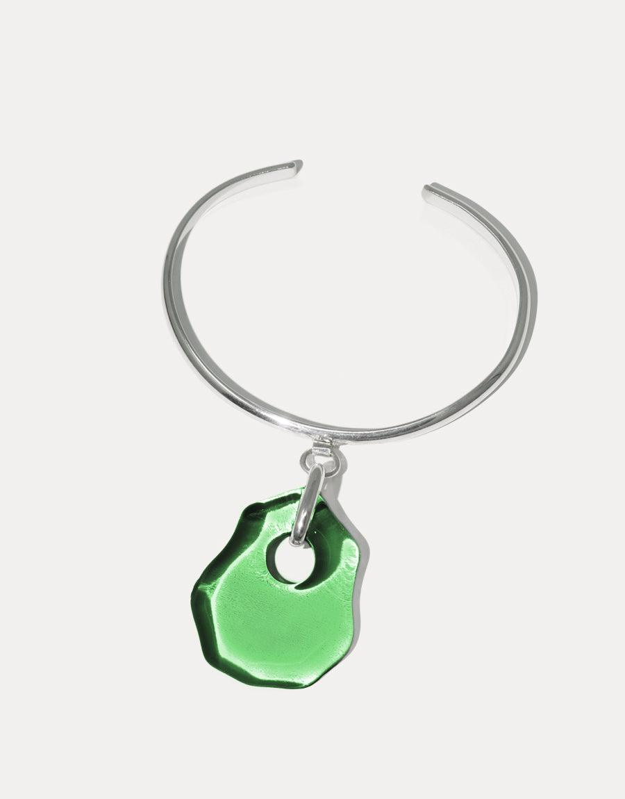 Elegant silver cuff bracelet featuring a vibrant green eco-friendly glass pendant, inspired by coastal shapes. Handcrafted Coastline Drop Bracelet showcases sustainable luxury and unique design. Perfect for ocean lovers and eco-conscious fashion enthusiasts. CLED