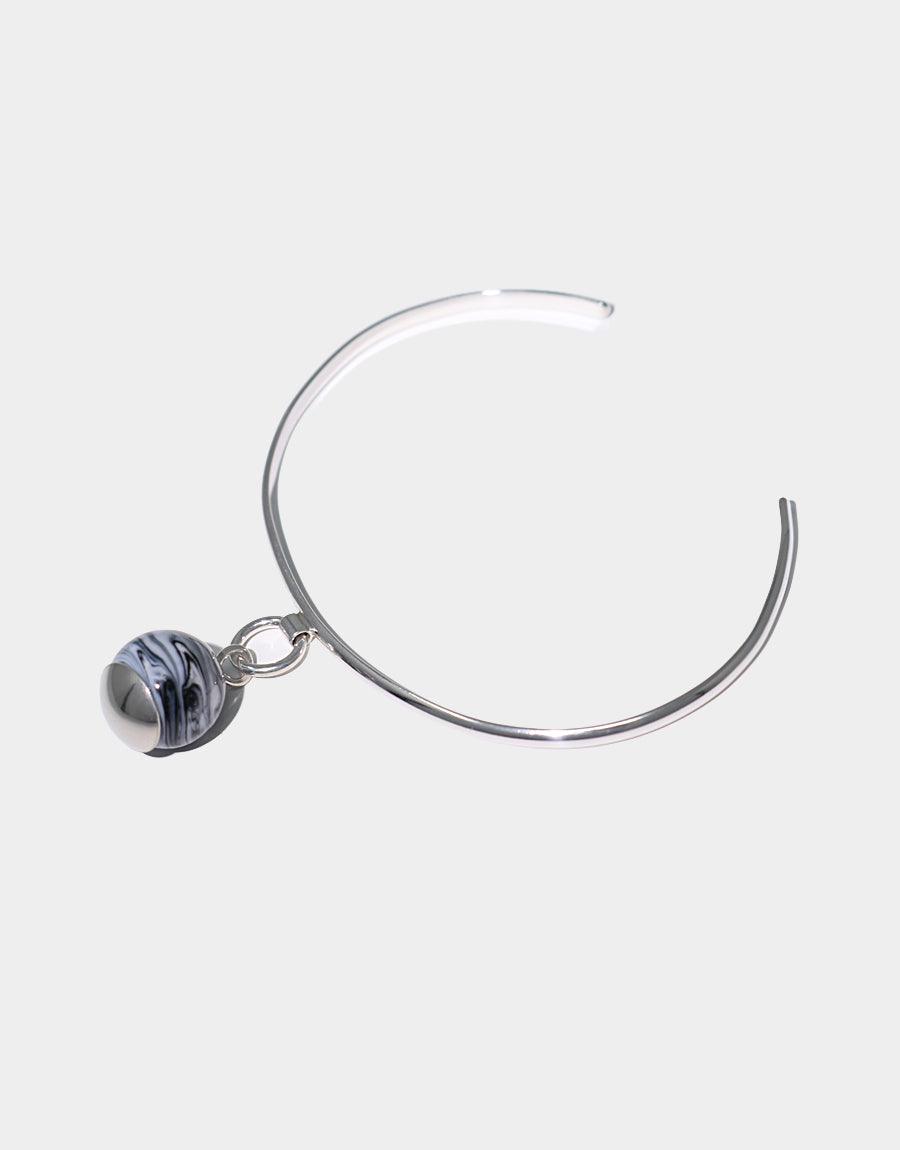 Elegant sterling silver Drop Bracelet featuring a minimalist cuff design with a suspended marble-like glass gem. Handcrafted in Los Angeles, this eco-conscious piece showcases repurposed glass for a unique, sustainable accessory. CLED